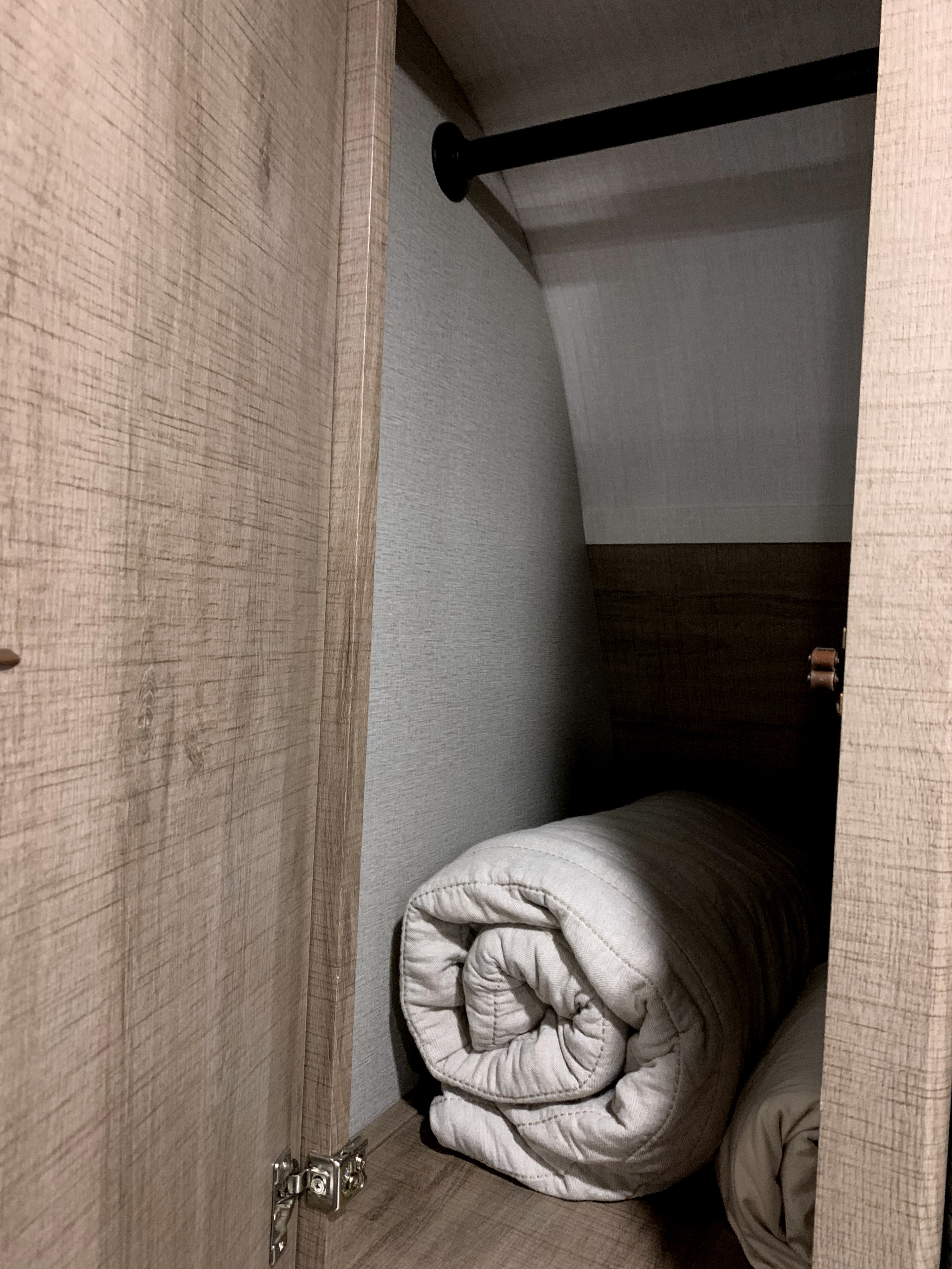 RV rental wardrobe interior: Rolled blankets neatly stored on a shelf with a clothes hanging rod above.. Grand Design Imagine XLS 2021