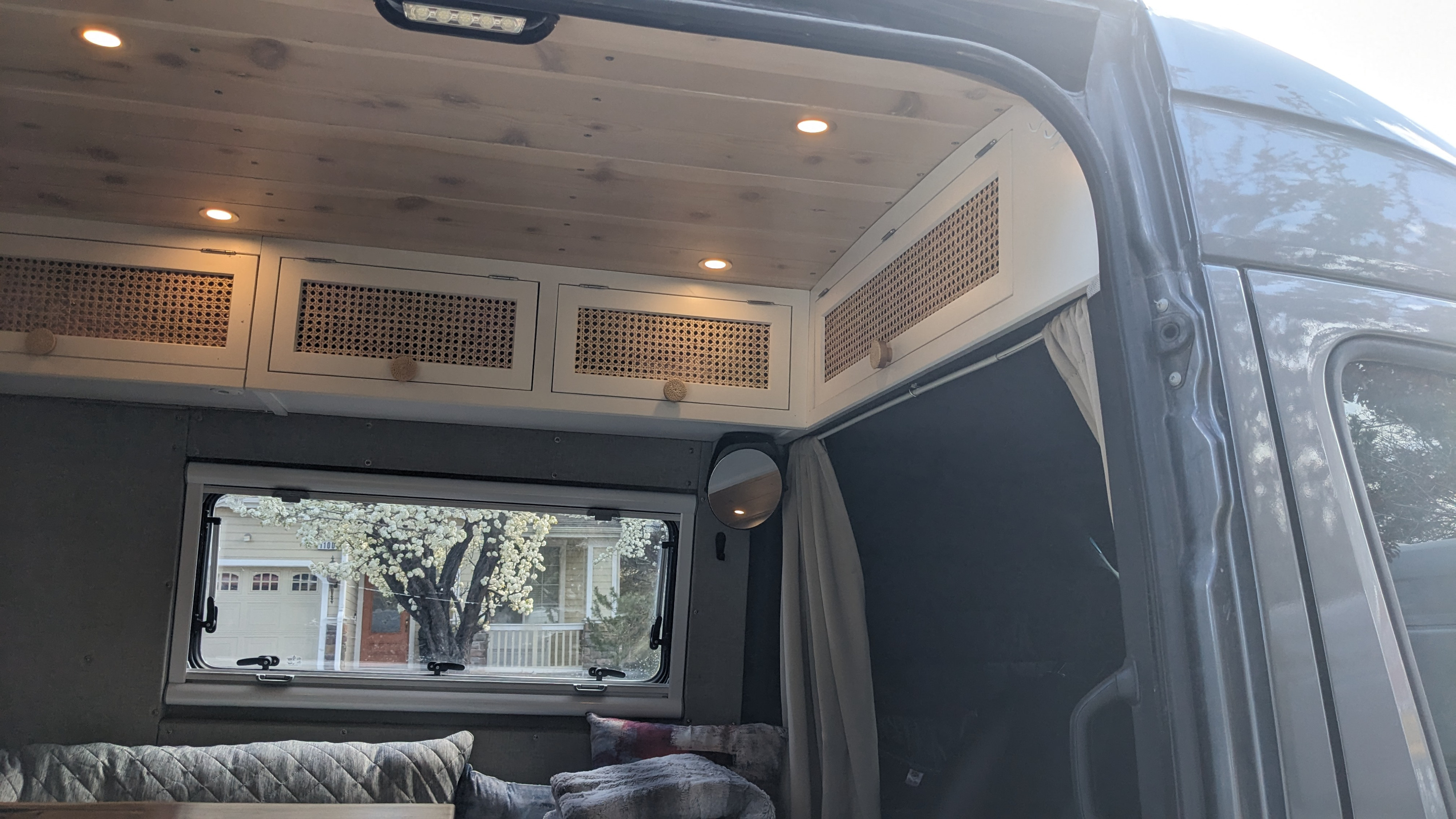 Cozy rv rental campervan interior: wood ceiling, rattan cabinets, window view, and soft seating for travelers.. Mercedes Sprinter 2021