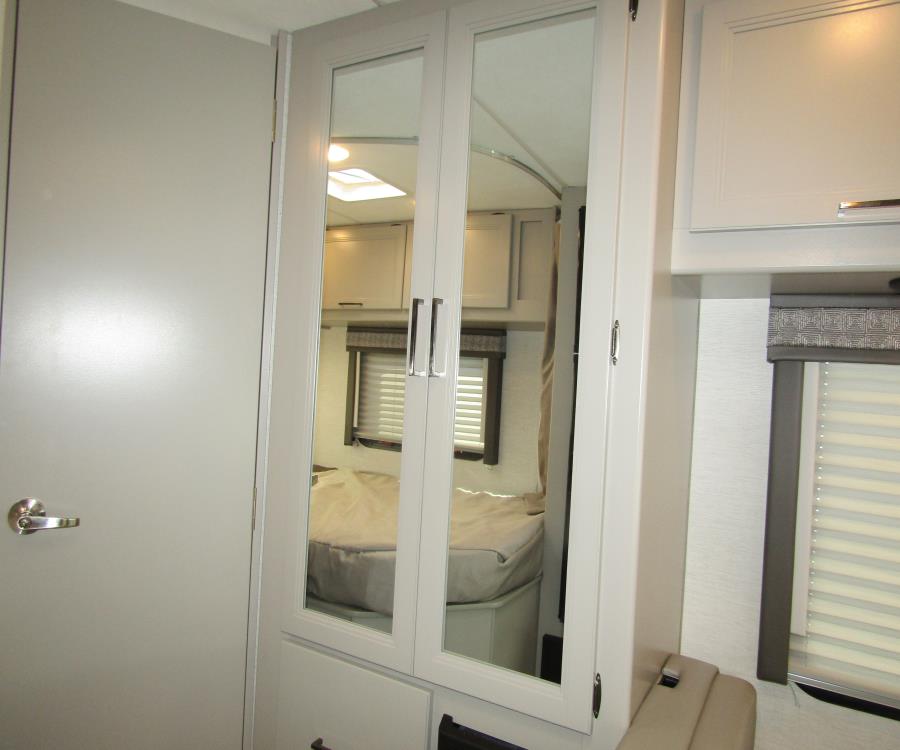 RV rental bedroom: Mirrored wardrobe, door, and window with blinds create a bright, functional space.. Thor Chateau 2025