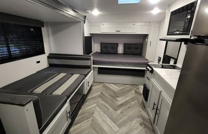 RV rental interior showcases a modern living space with convertible beds, a kitchen, and stylish gray-and-white decor.. Forest River Salem FSX 2021