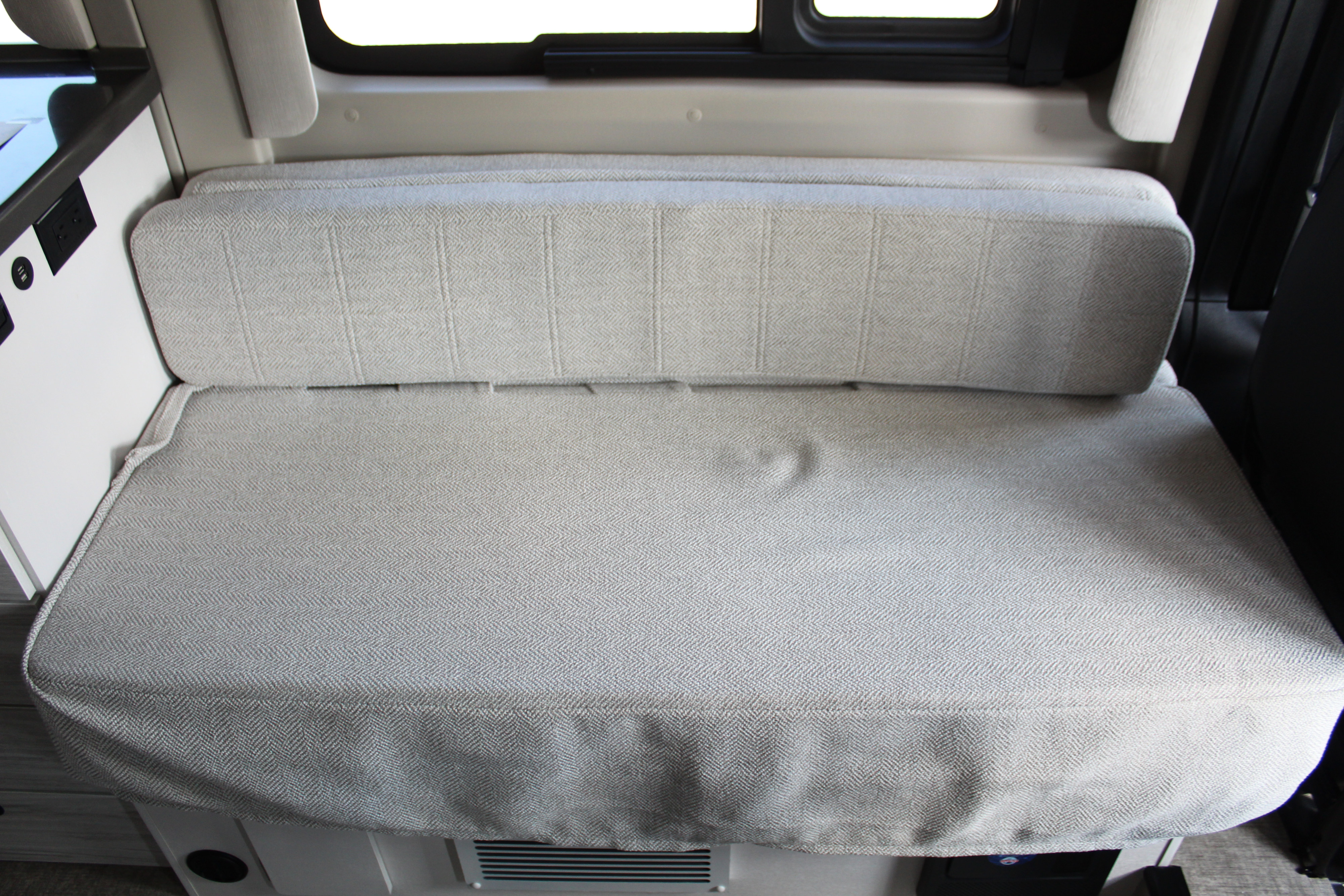 Cozy rv rental bench seating with light herringbone fabric and convenient power outlets, ideal for travel comfort.. Entegra Coach Arc 2025