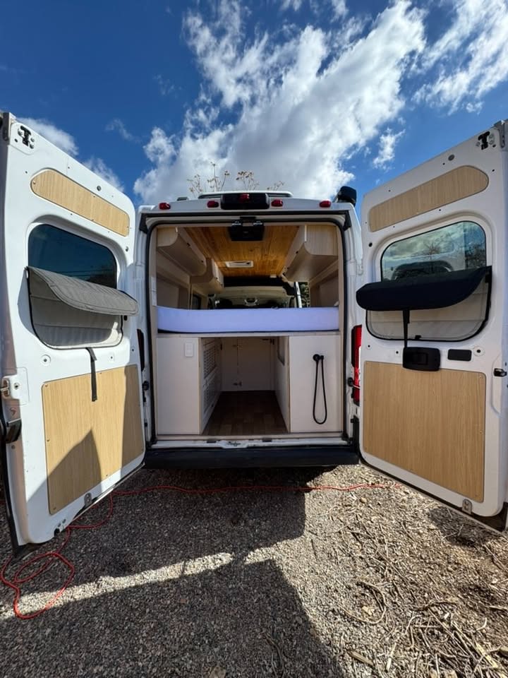 Back of an RV rental camper van with open doors, revealing a bed & storage. Ready for your mobile living adventure.. Dodge 1500 2019
