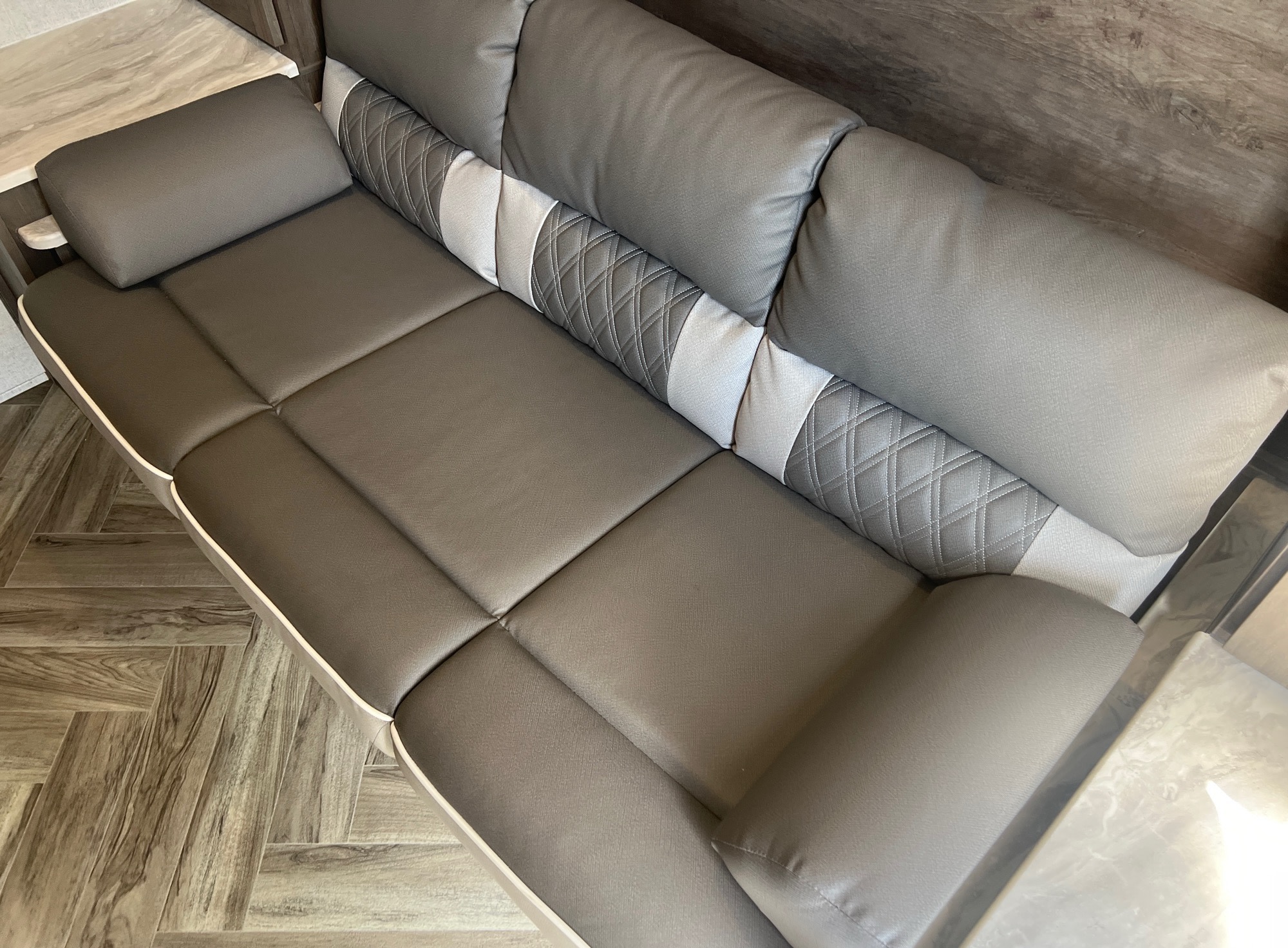 Modern gray sofa in an RV rental, featuring textured cushions and a stylish backrest with quilted and plain sections.. Forest River Wildwood X-Lite 2021