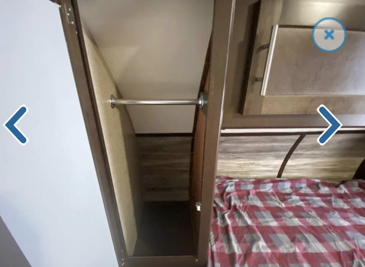 RV rental: Compact bedroom closet with a hanging rod, next to a bed with a red plaid comforter.. Forest River Cherokee 2018