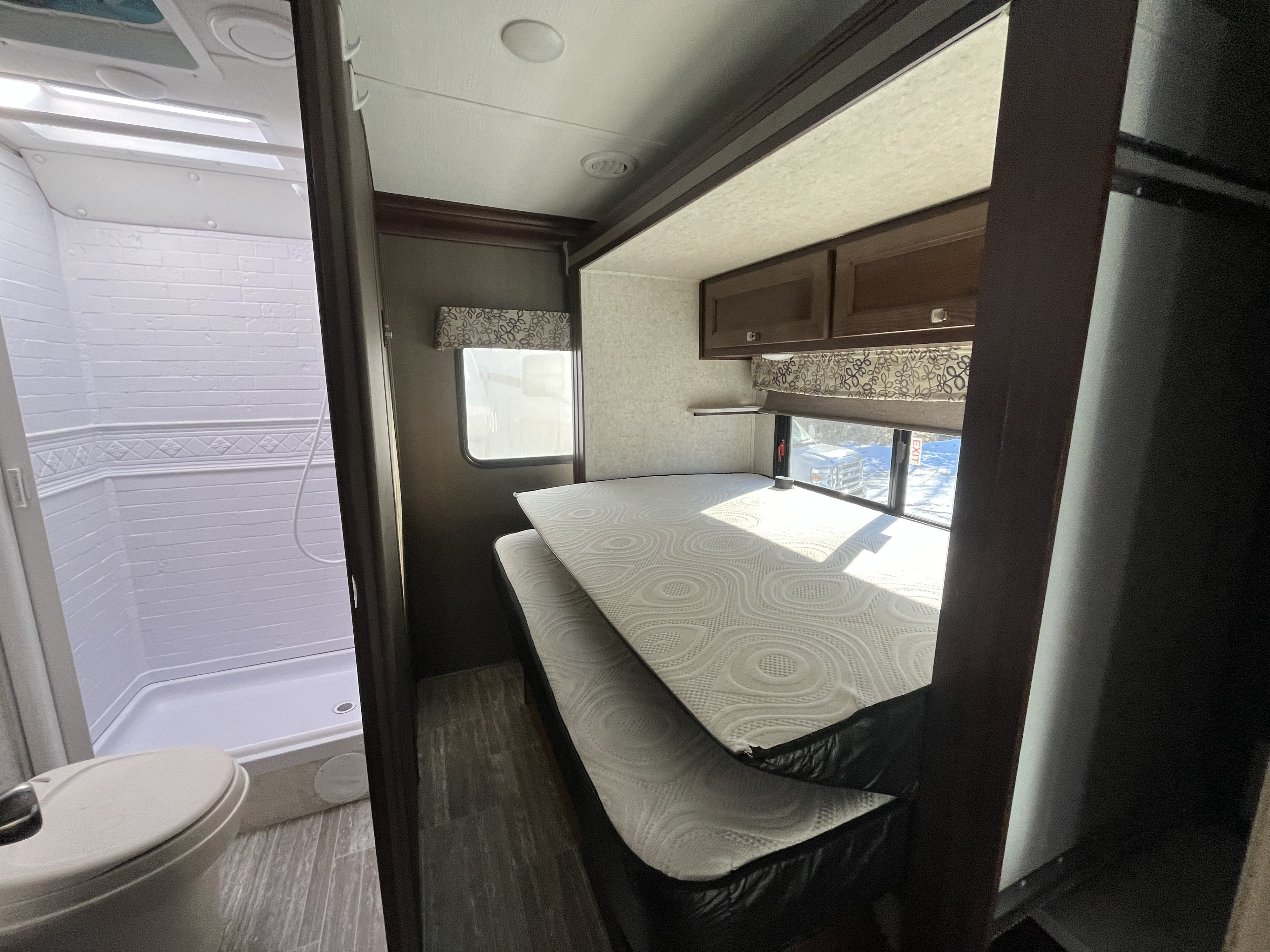 This RV rental features a cozy bedroom with bunk beds, overhead storage, and an adjacent compact bathroom with a shower and toilet.. Forester Forester Motorhome 2020