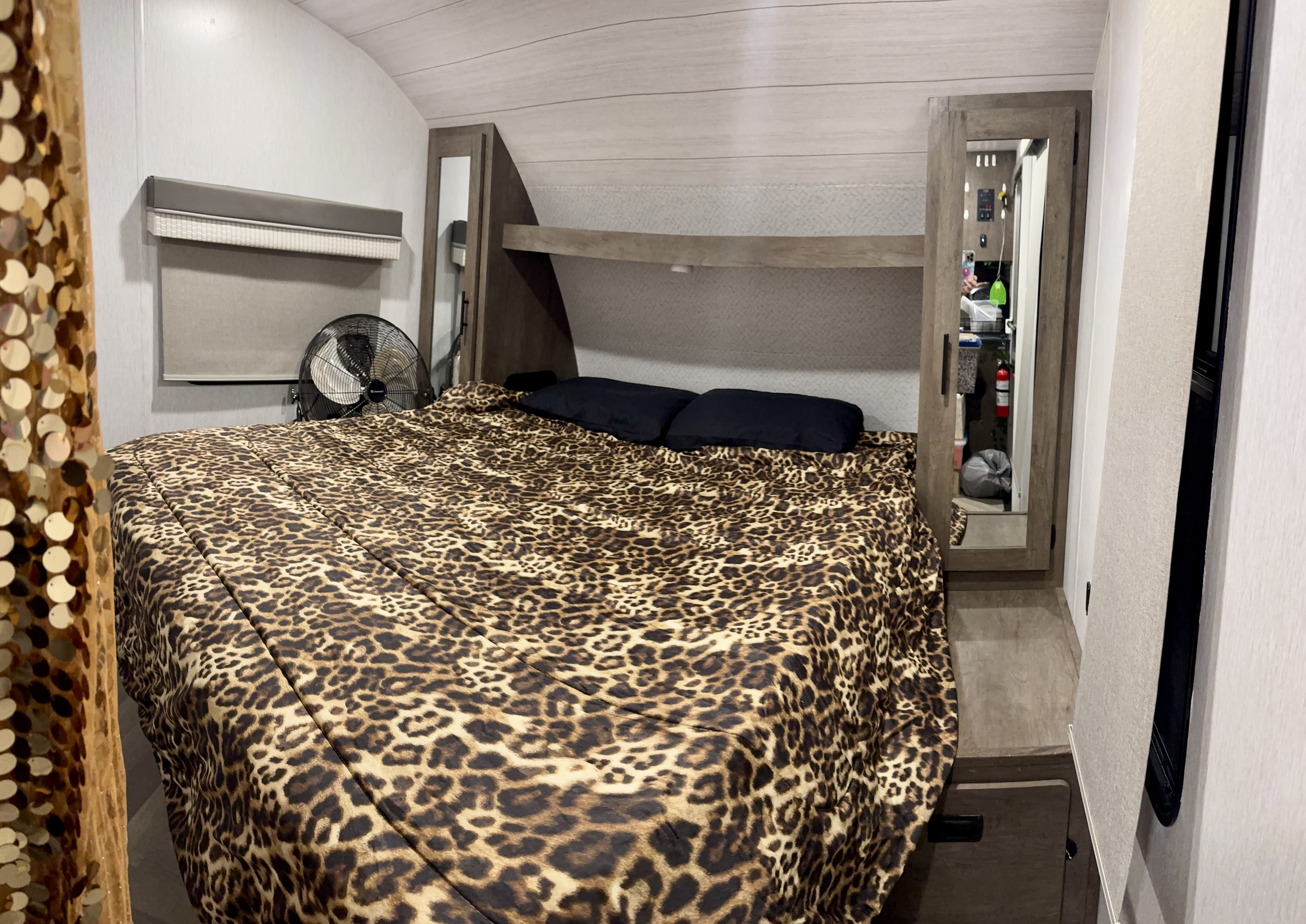 Cozy RV rental bedroom features a leopard print bed, fan, and compact storage with mirrors.. Forest River Wildwood X-Lite 2022