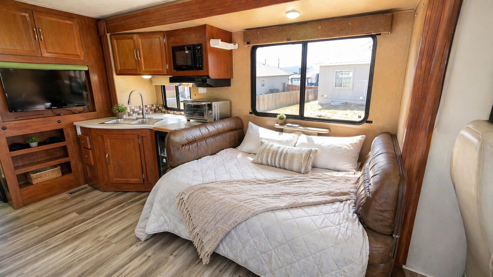 Cozy RV rental interior: kitchen with a sink, microwave, toaster oven, and a comfortable bed with TV and storage.. Coachmen Pursuit 2014