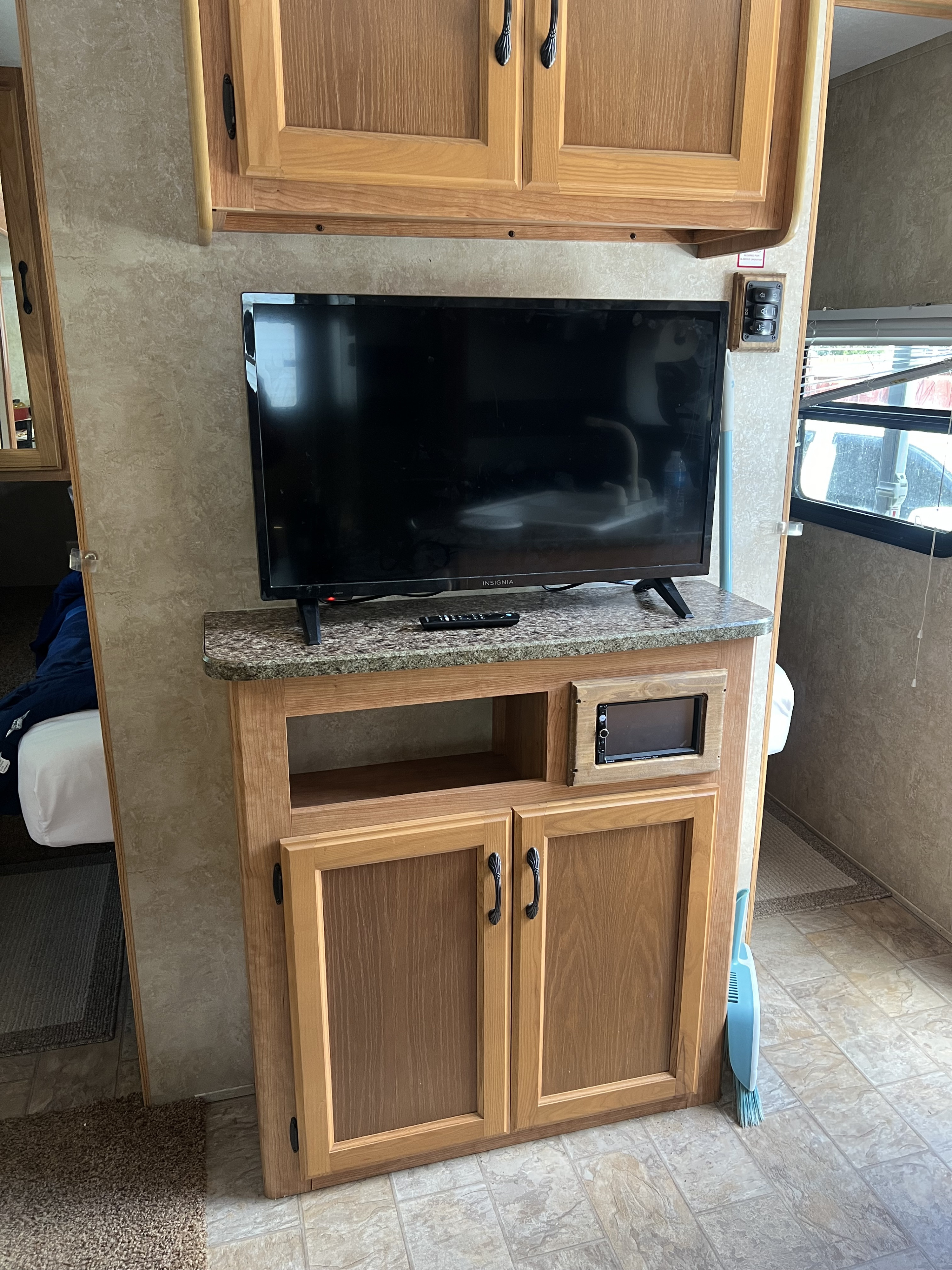 RV rental interior features a TV on a faux-granite counter, light wood cabinets, and an audio system. Notice the compact living space.. Keystone RV Sprinter Select 2010