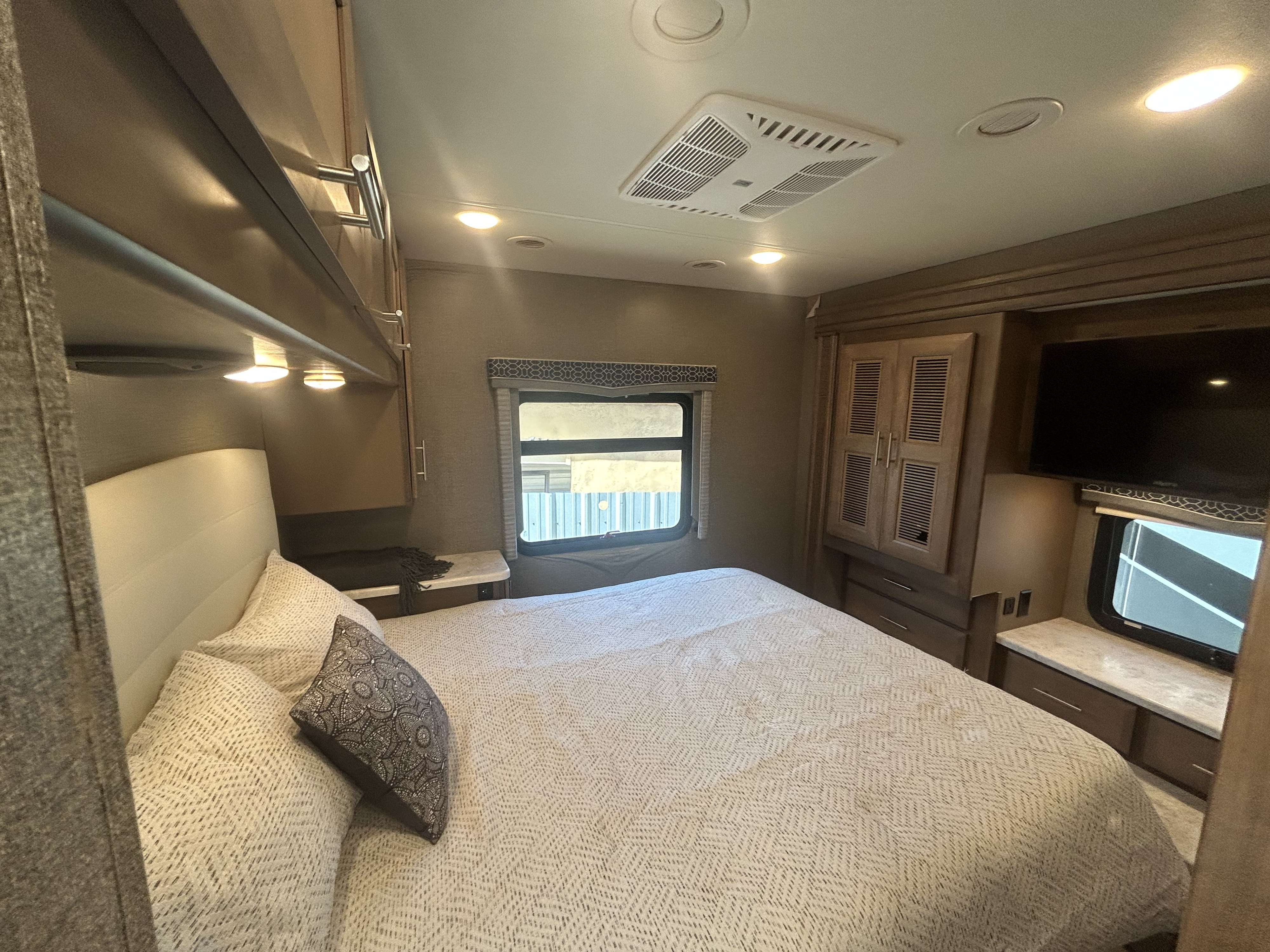 Cozy RV rental bedroom with comfortable bed, TV, overhead AC, and storage. Perfect for restful nights on the road.. Thor Magnitude 2021