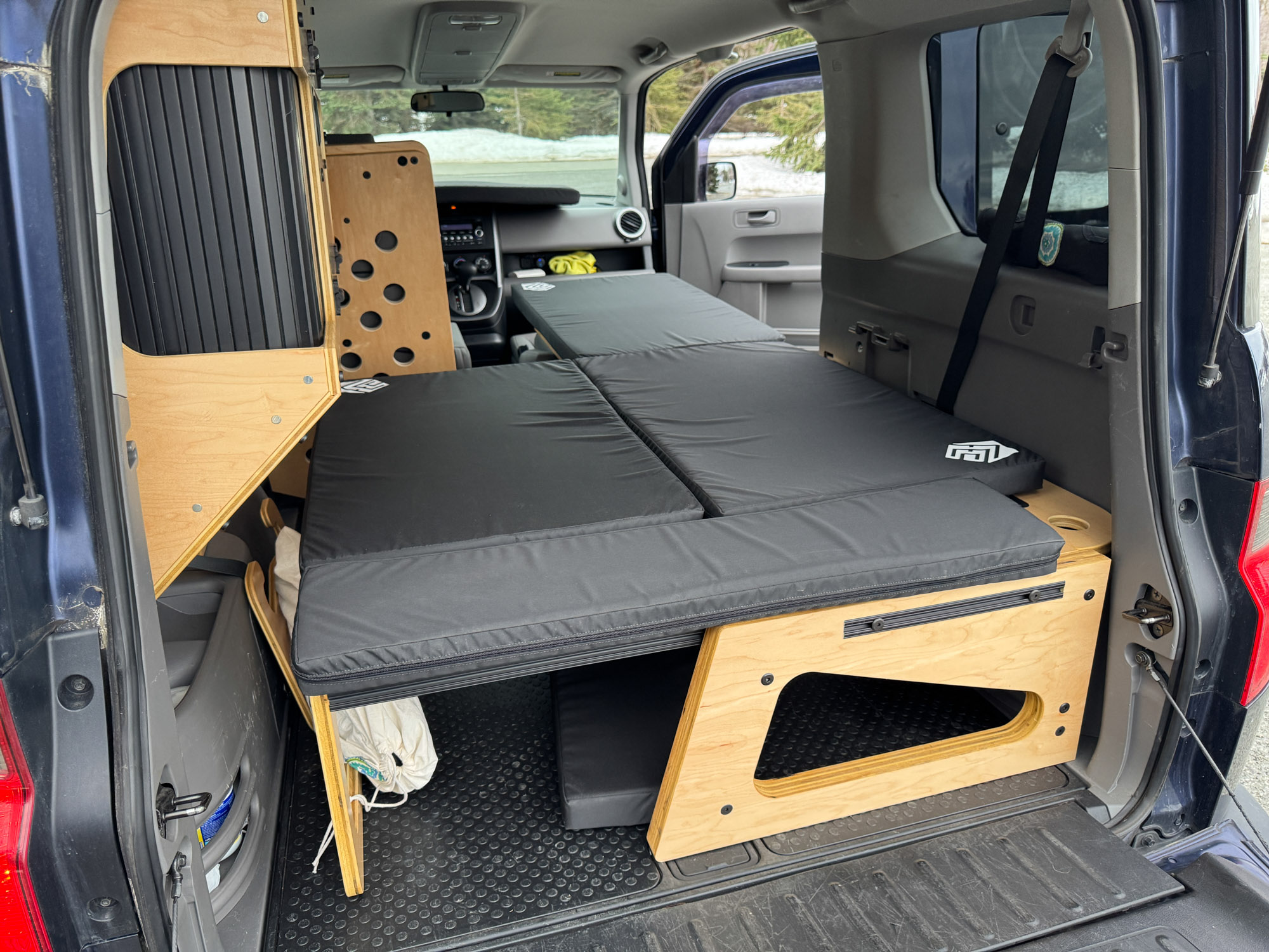 Inside a custom car camper setup: modular wooden sleeping platform & storage for adventurous rv rental trips.. Honda Element 2010