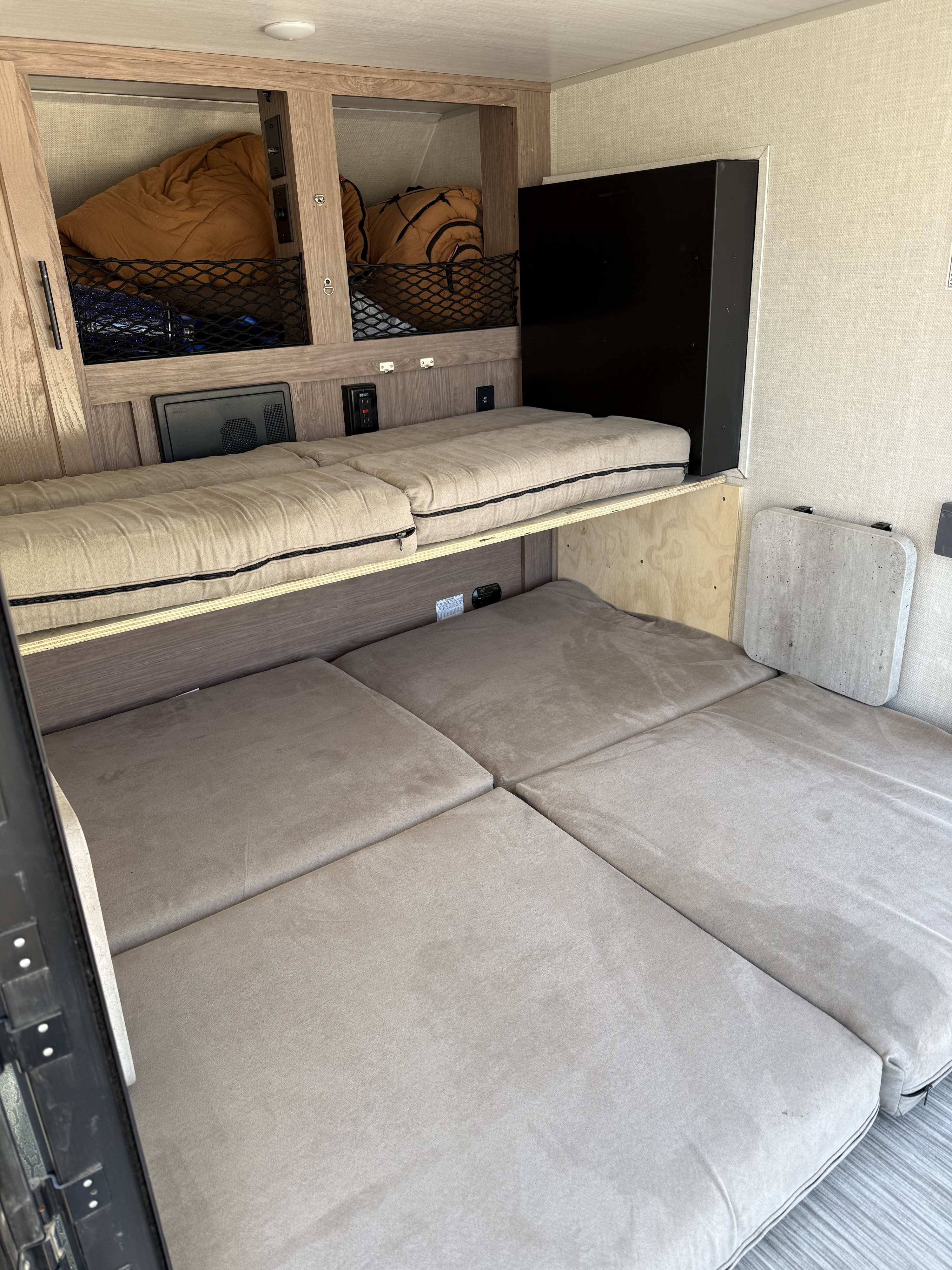 RV rental interior featuring upper and lower bunk beds, built-in storage nets, and a wall-mounted table.. No Boundaries 10 Toy Hauler 2022