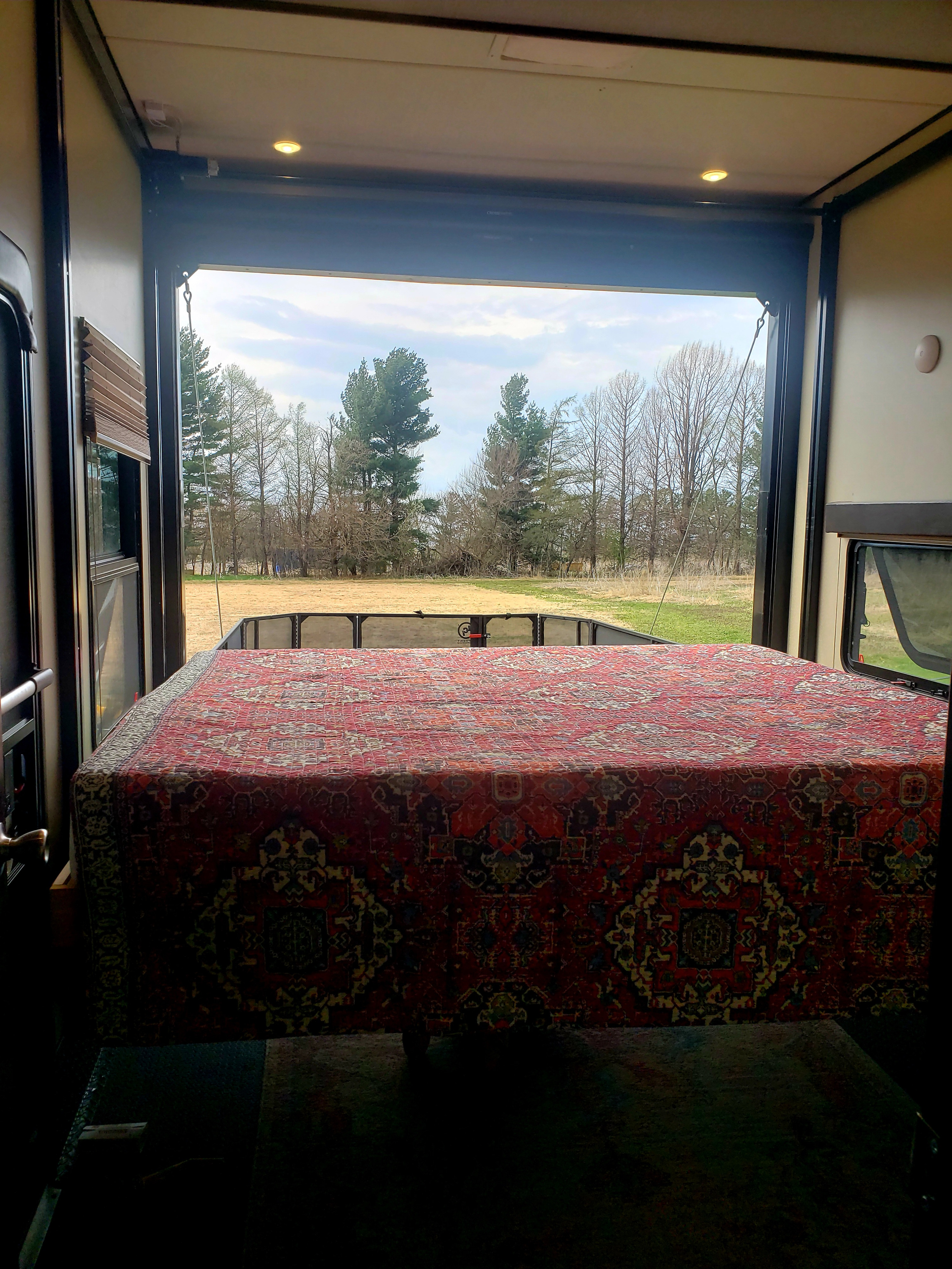 Enjoy nature from your RV rental! Open rear door reveals a unique rug-covered bed & a view of trees/field.. Grand Design Momentum 2017