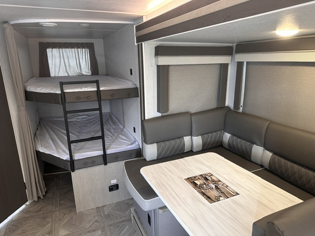 RV rental: Spacious interior featuring cozy bunk beds with a ladder and a comfortable U-shaped dinette with a table.. Forest River Wildwood X-Lite 2023