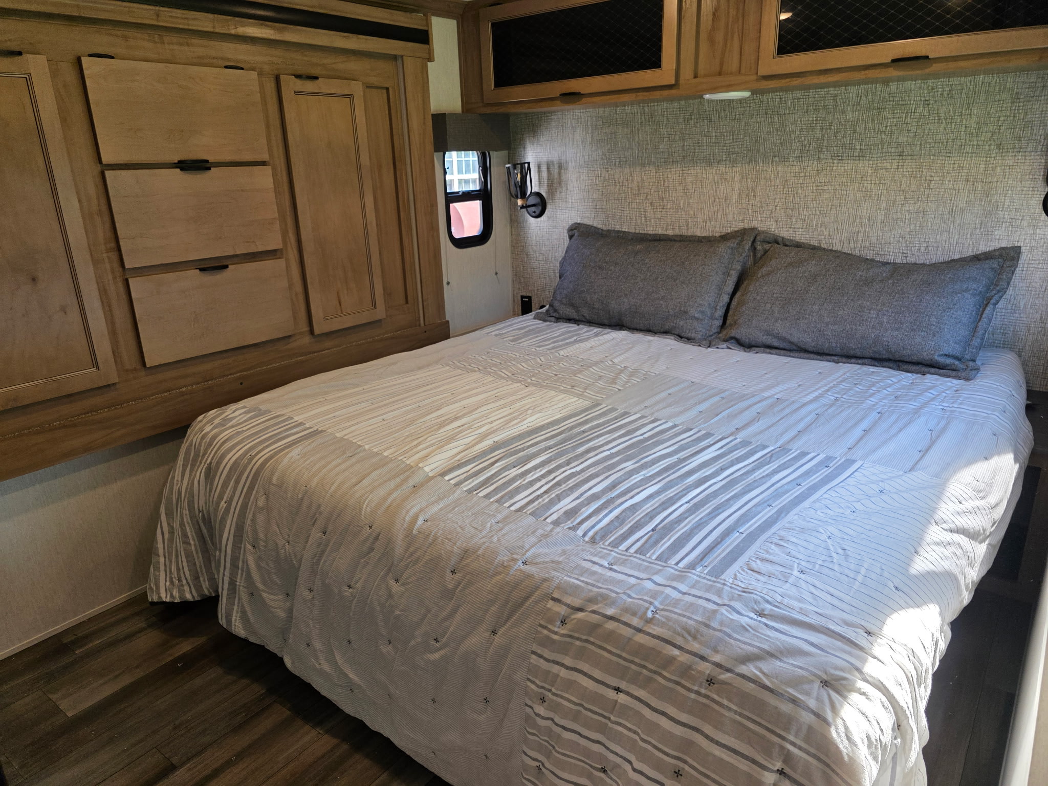 Cozy RV rental bedroom featuring a comfortable bed with striped bedding, built-in storage, and ambient lighting.. Forest River Sabre 2024