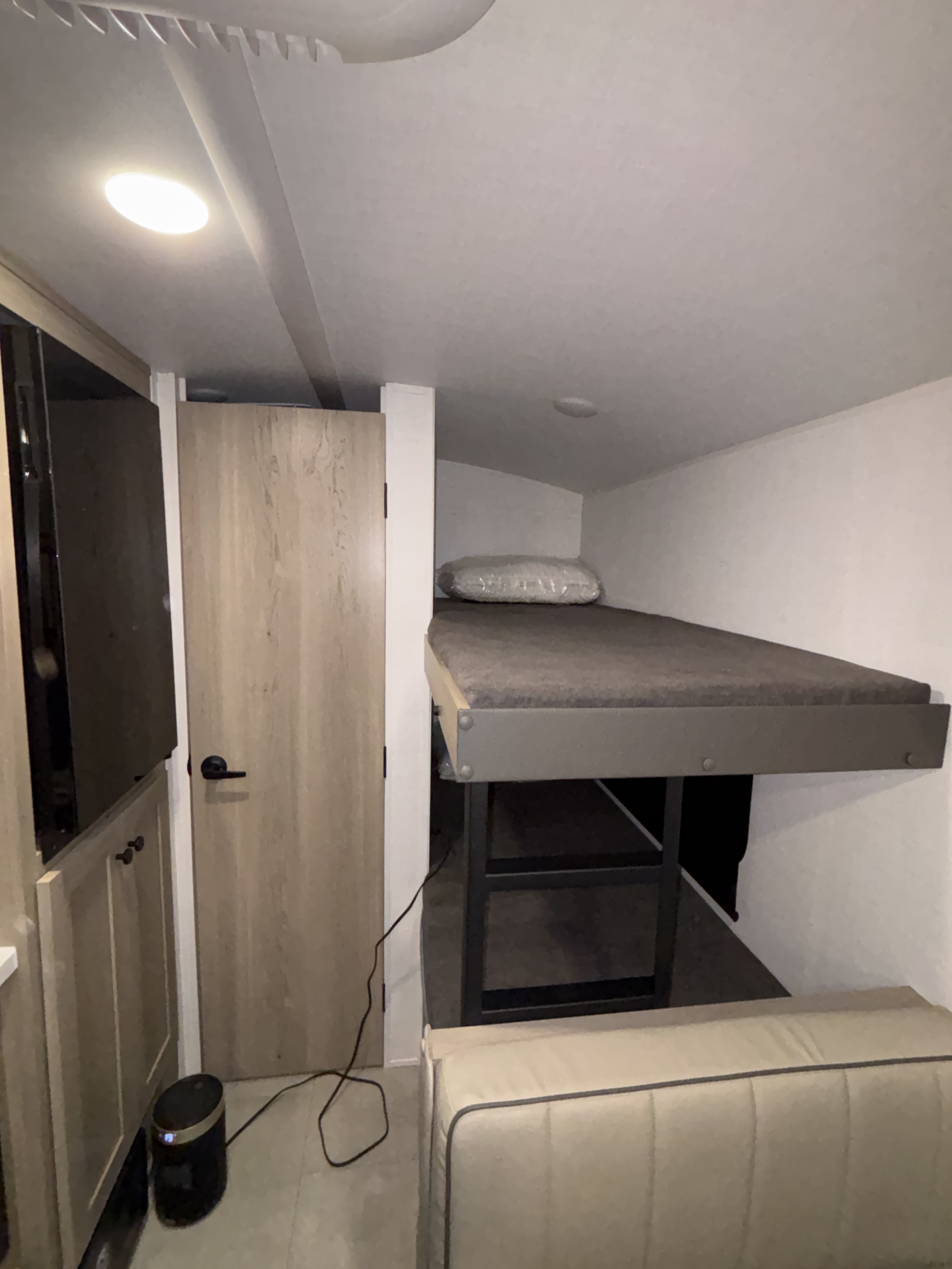 RV rental with a cozy bunk bed (grey mattress, pillow in plastic), seating below, wood door, and floor fan.. Forest River Geo Pro 2026