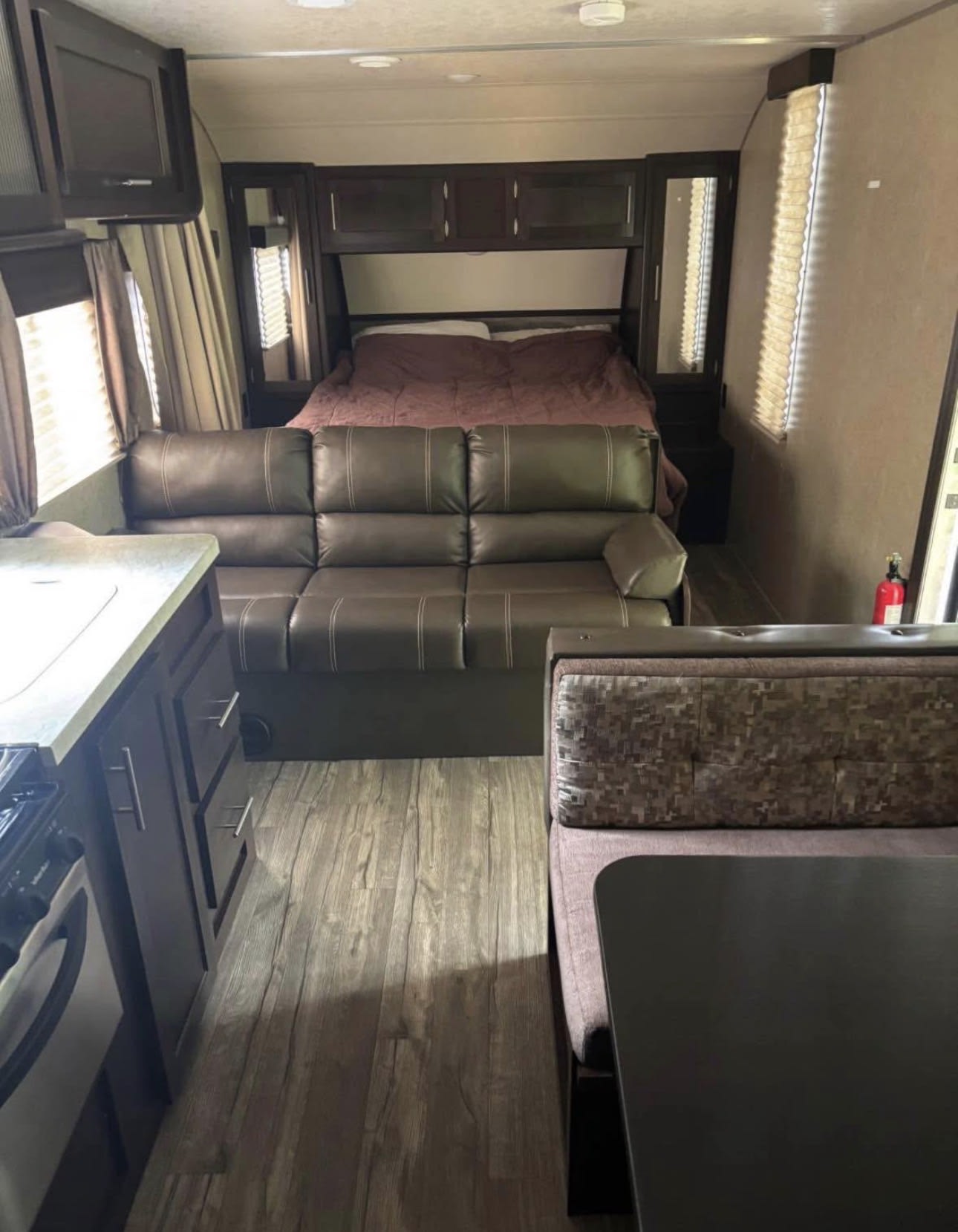 This rv rental interior features a kitchen, brown leatherette sofa, bed, and dinette area, with wood-look flooring throughout.. Forest River Cherokee Grey Wolf Special Edition 2018