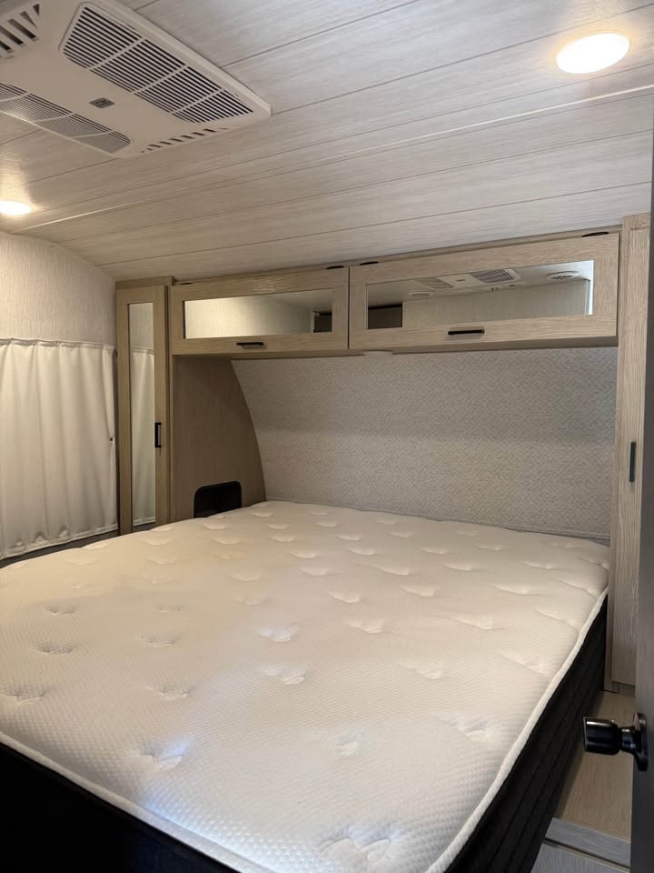 RV rental bedroom featuring a large mattress, overhead mirrored cabinets, and ceiling AC. Comfortable and ready for travel.. Forest River Salem 2024