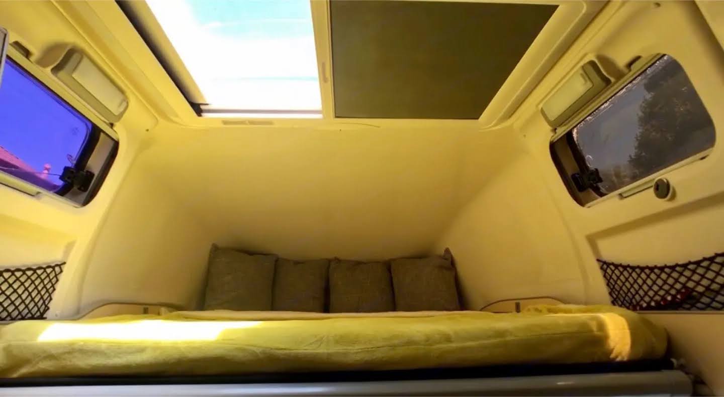 Cozy RV rental interior with a bed, pillows, large skylight, windows, and storage nets. Perfect for your next adventure.. Airstream Airstream Class B 2005
