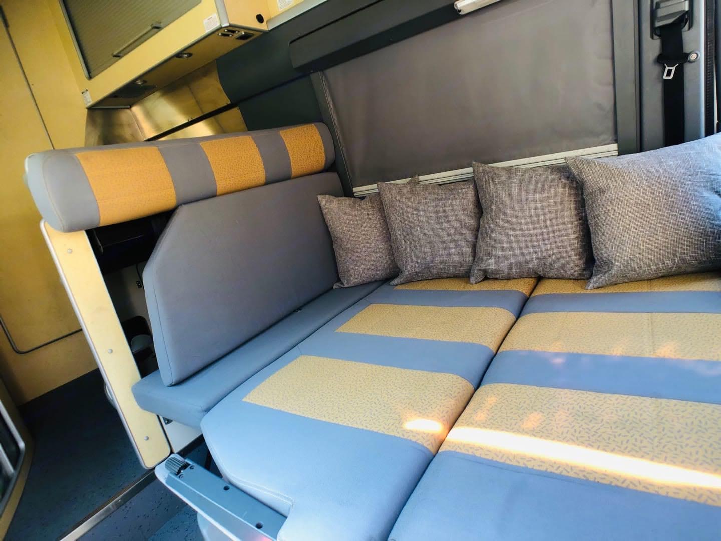 Cozy rv rental interior: comfortable seating and bed setup with gray & yellow striped cushions and throw pillows.. Airstream Airstream Class B 2005