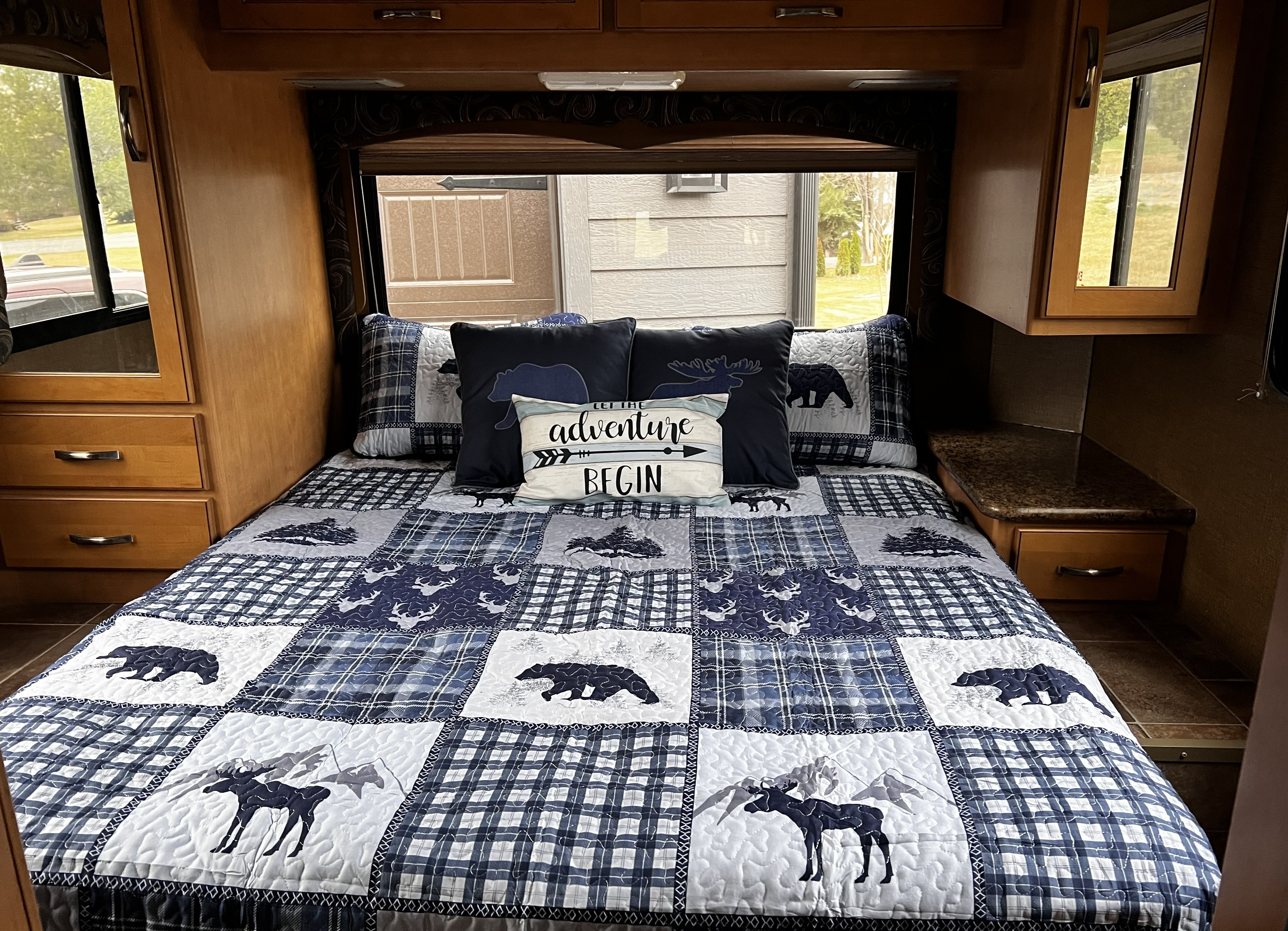 Enjoy this RV rental's cozy bedroom with a wilderness-themed quilt, bear & moose patterns, and an "Adventure Begin" pillow.. Thor Four Winds 2015