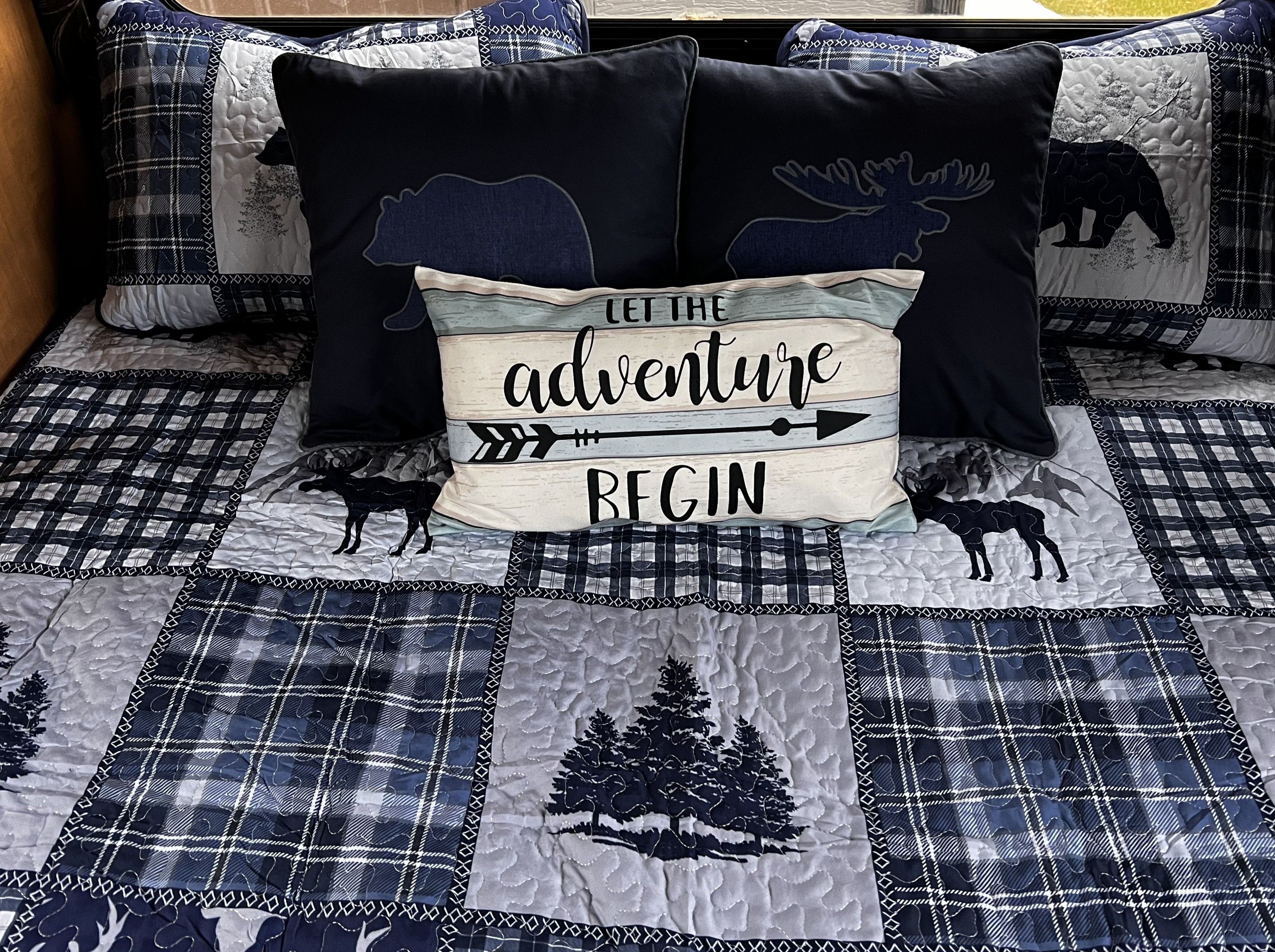 Adventure-themed bedding, featuring plaid, bears, moose, and a 'LET THE adventure BEGIN' pillow, perfect for an RV rental or cabin.. Thor Four Winds 2015