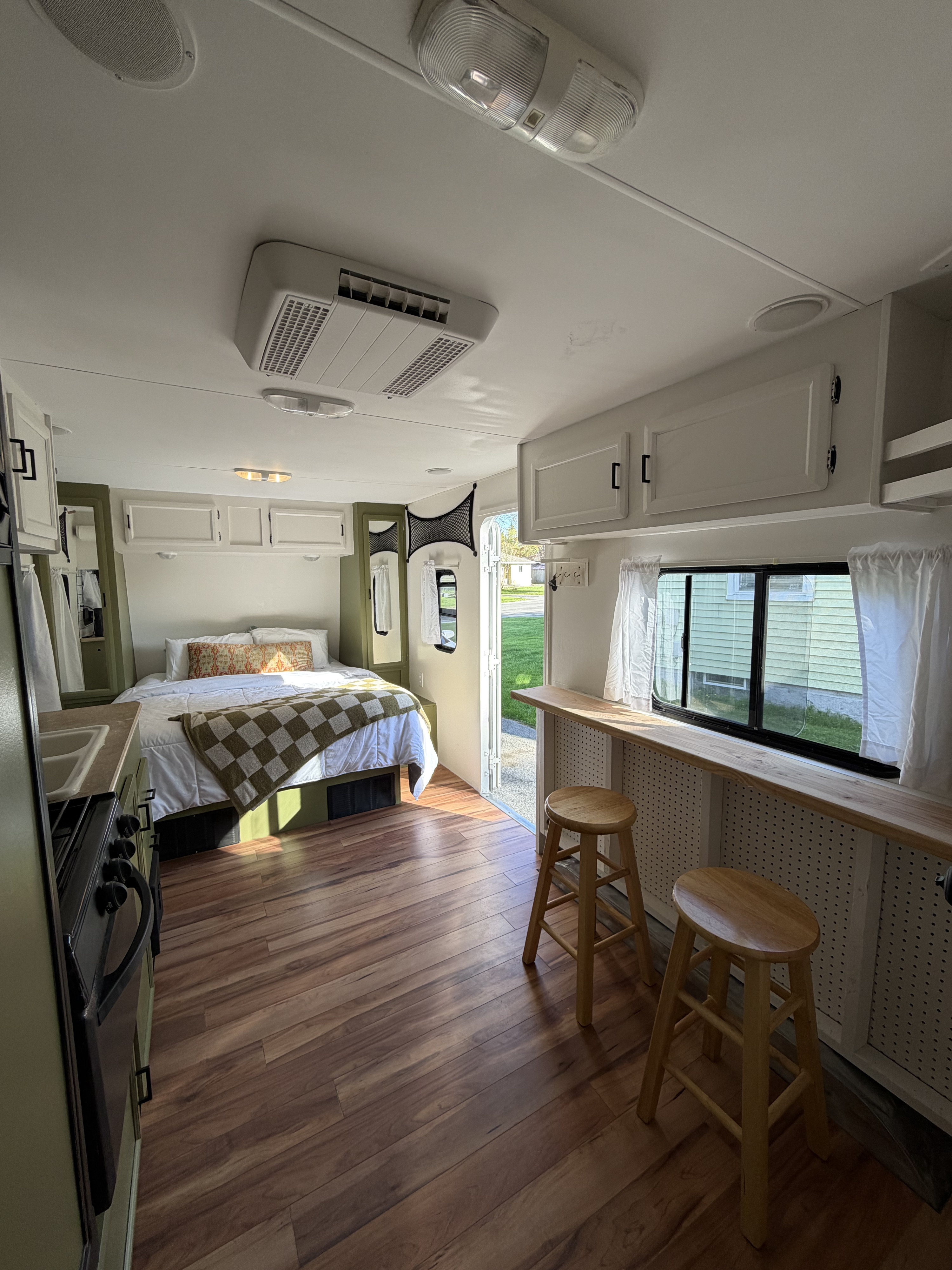 Inside an rv rental: a cozy bedroom, compact kitchen with a stove, and a dining bar with stools, all on hardwood floors.. KZ Sportsmen 2011