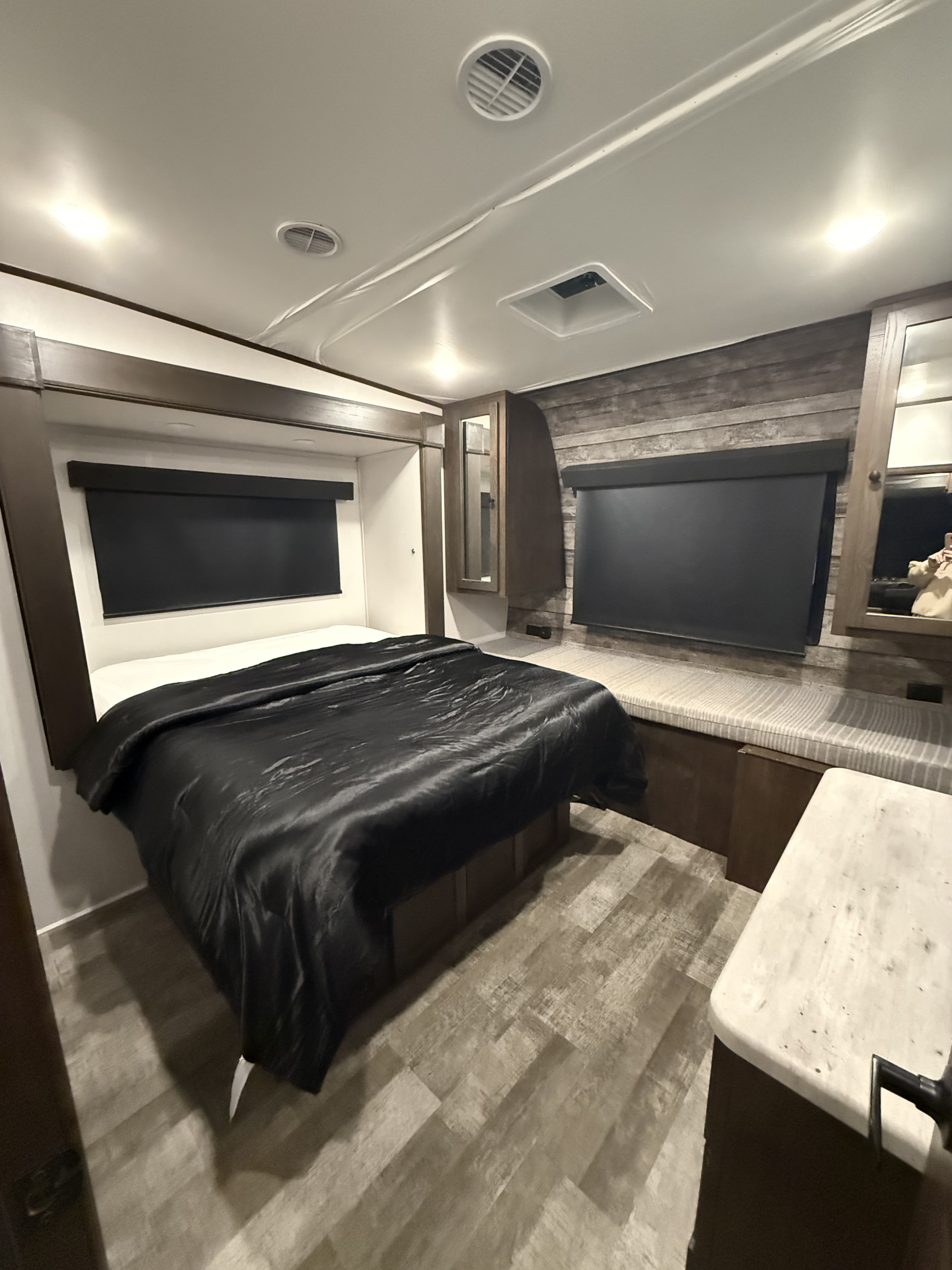 Cozy rv rental bedroom featuring a bed with black bedding, wood-paneled walls, built-in storage, and modern overhead lighting.. Forest River Hyper lite XLR 2022