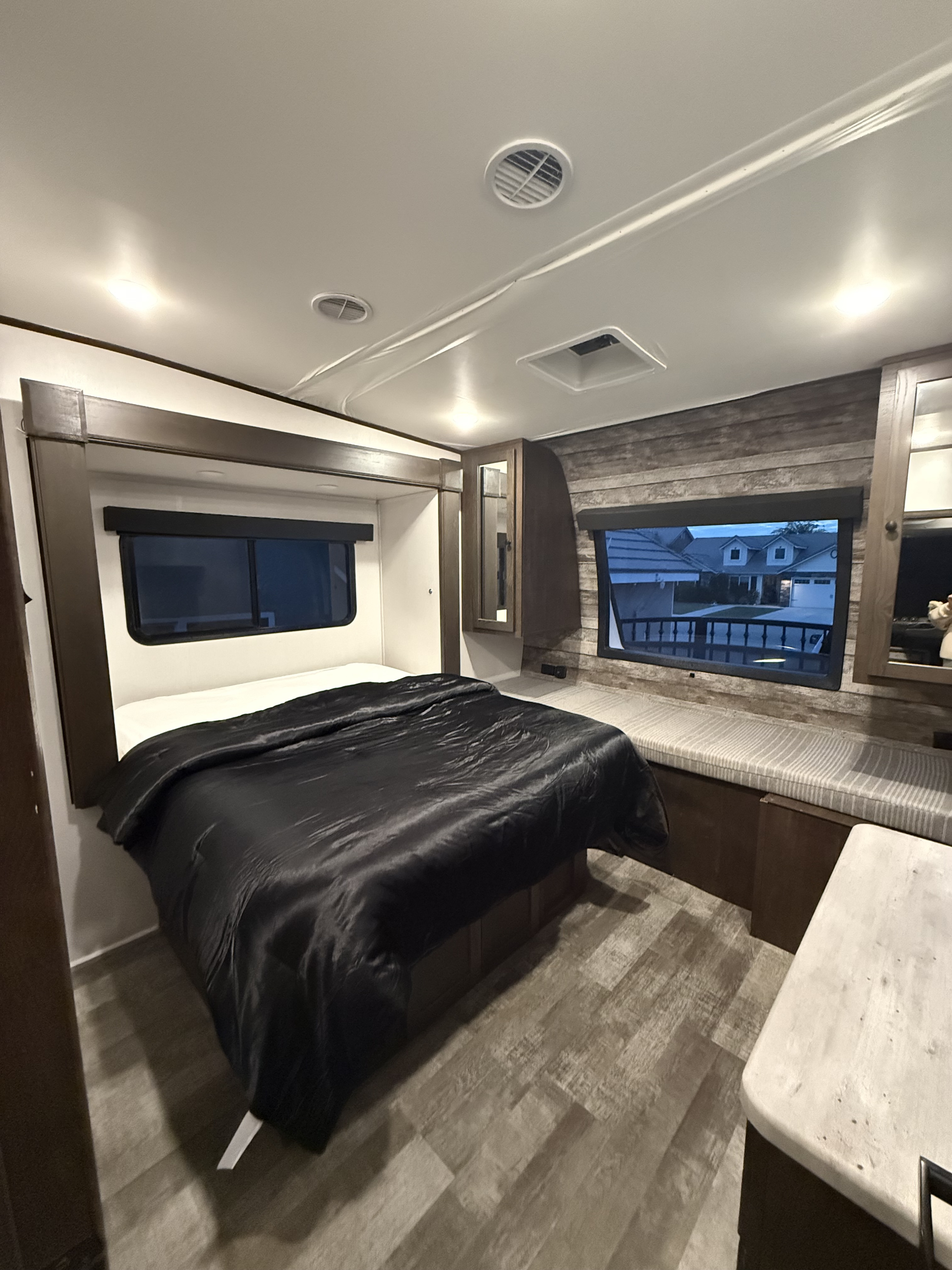 Spacious RV rental bedroom with a large bed, modern wood paneling, windows, and comfy bench seating for your travels.. Forest River Hyper lite XLR 2022