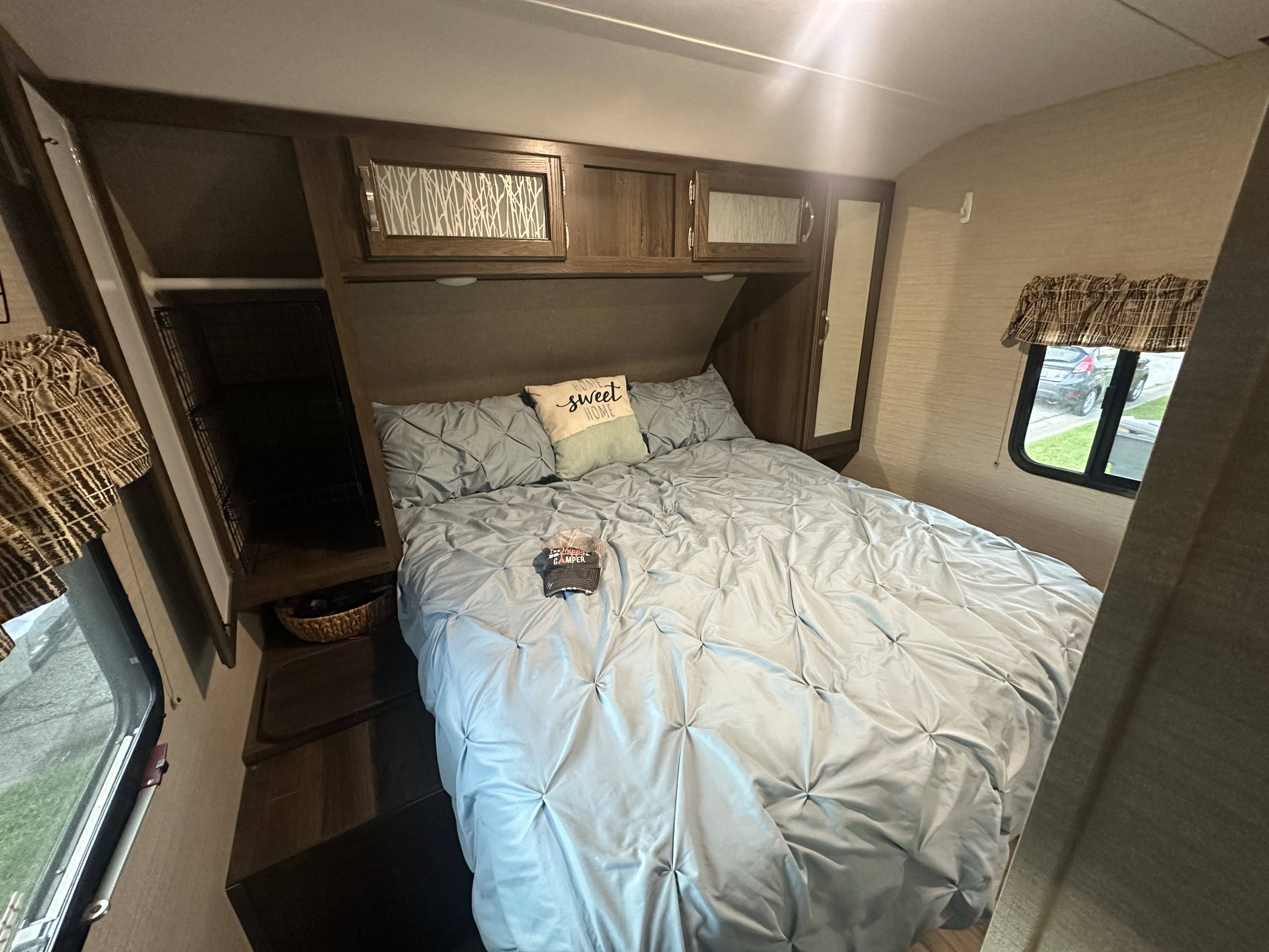 Cozy RV rental bedroom with a comfy bed, "home sweet home" pillow, and overhead storage.. Keystone RV Bullet Ultra Lite 2019