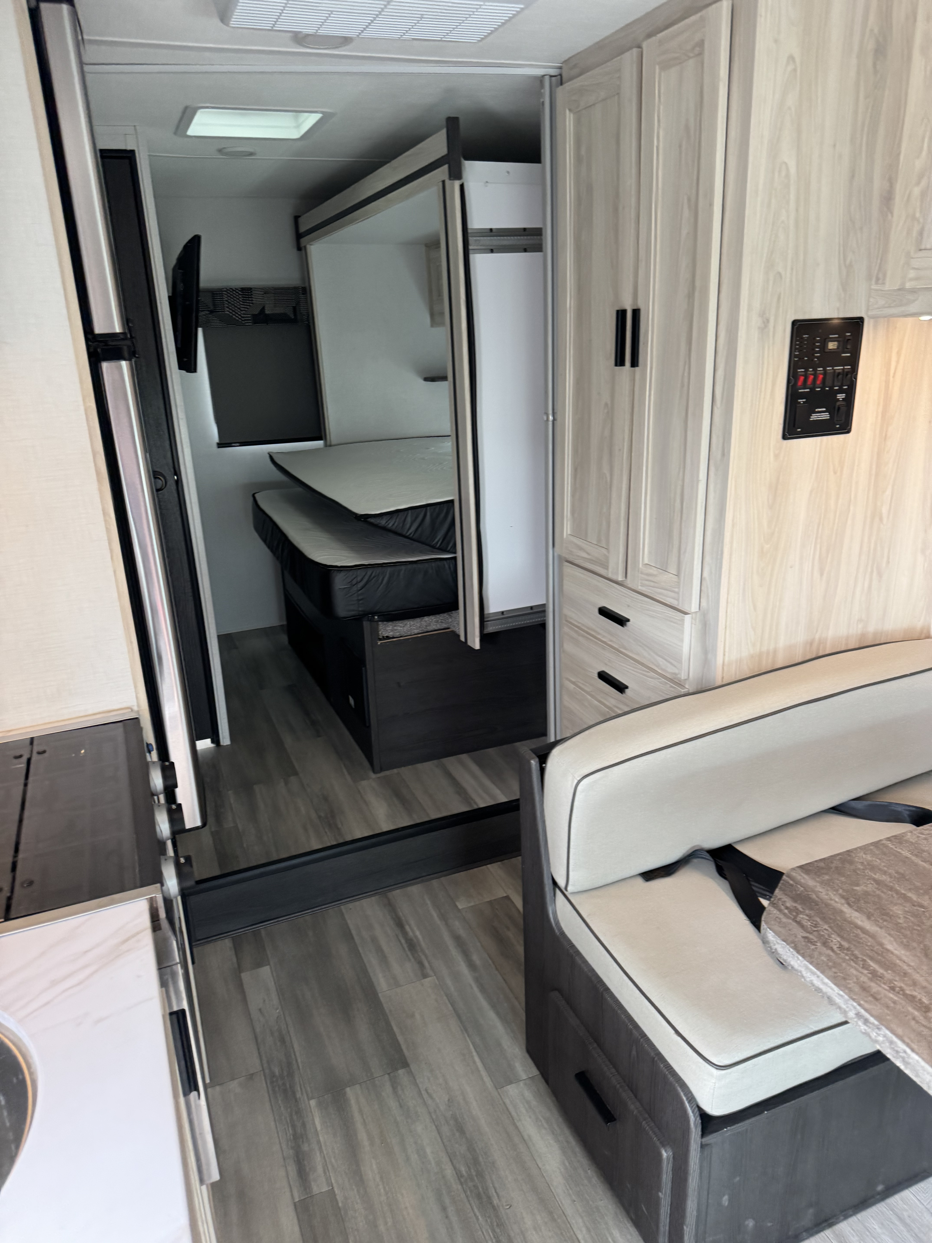 An rv rental interior with bunk beds, light wood cabinetry, a dinette, and modern flooring, ready for your next adventure.. Forest River Sunseeker LE 2023