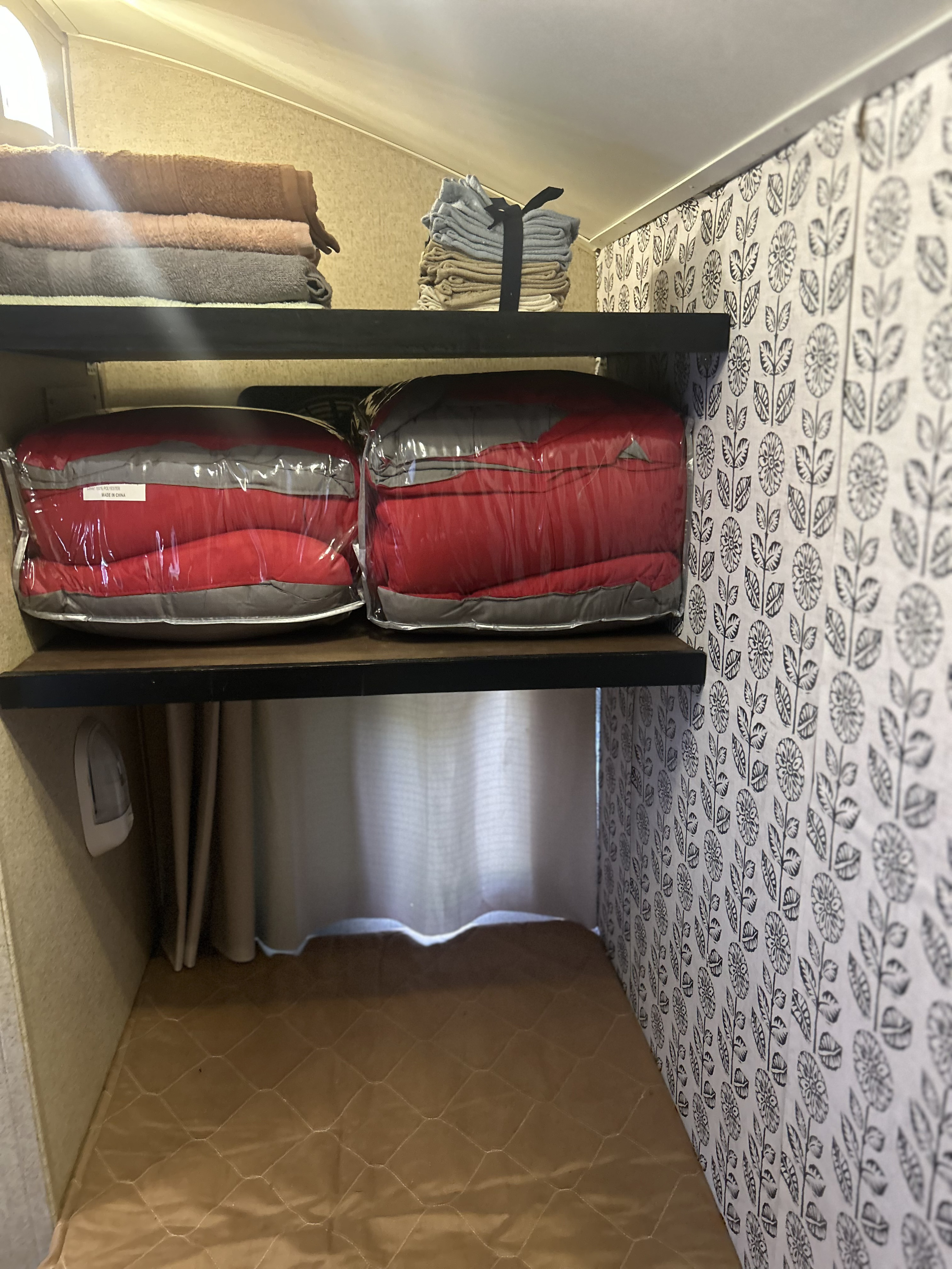 RV rental bunk space: shelves with neatly folded towels, packaged sleeping bags, a night light, and floral wallpaper.. R-Pod R-Pod Trailer 2014