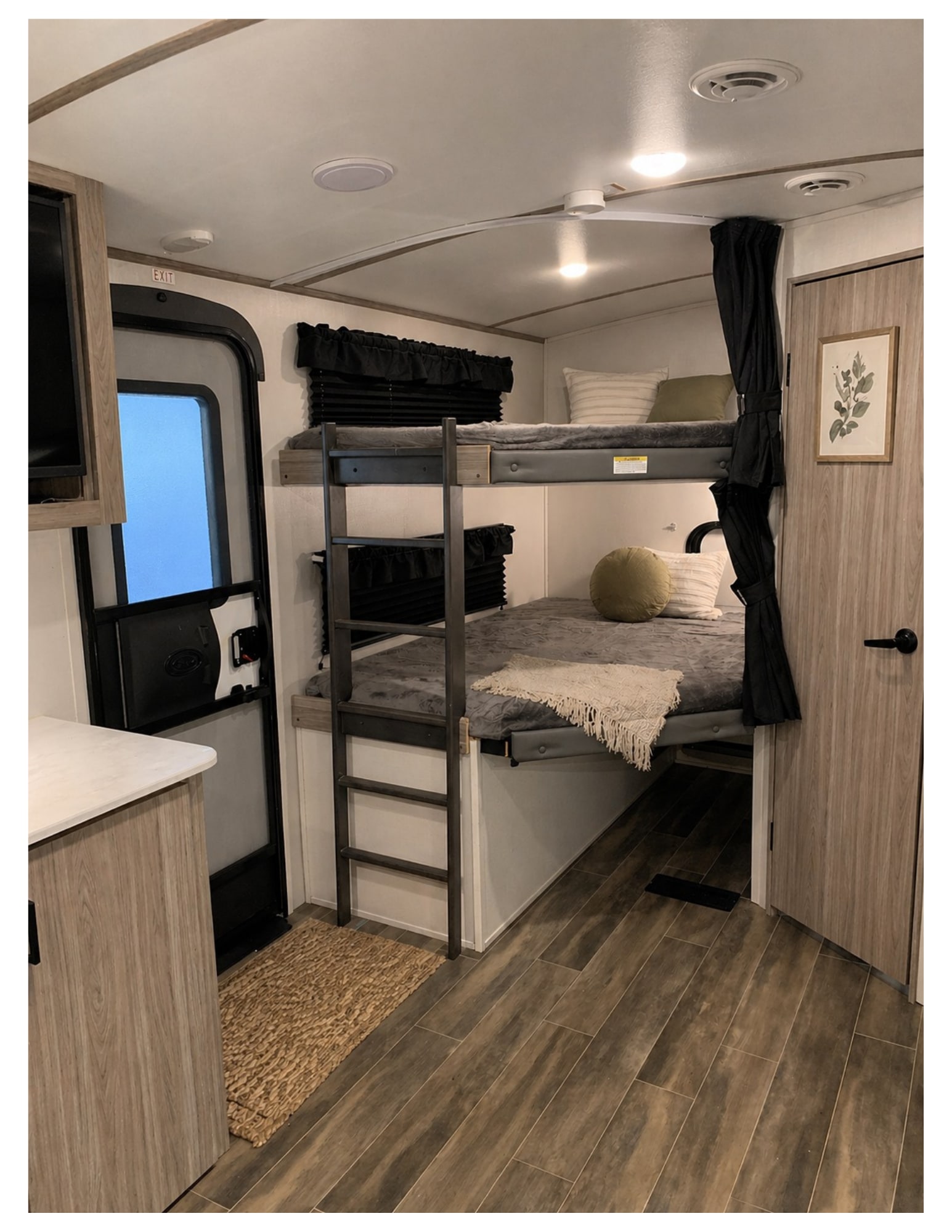 Relax in this RV rental's cozy interior, featuring bunk beds with a ladder, plush bedding, wood-look flooring, and thoughtful details.. Keystone RV Passport 2022
