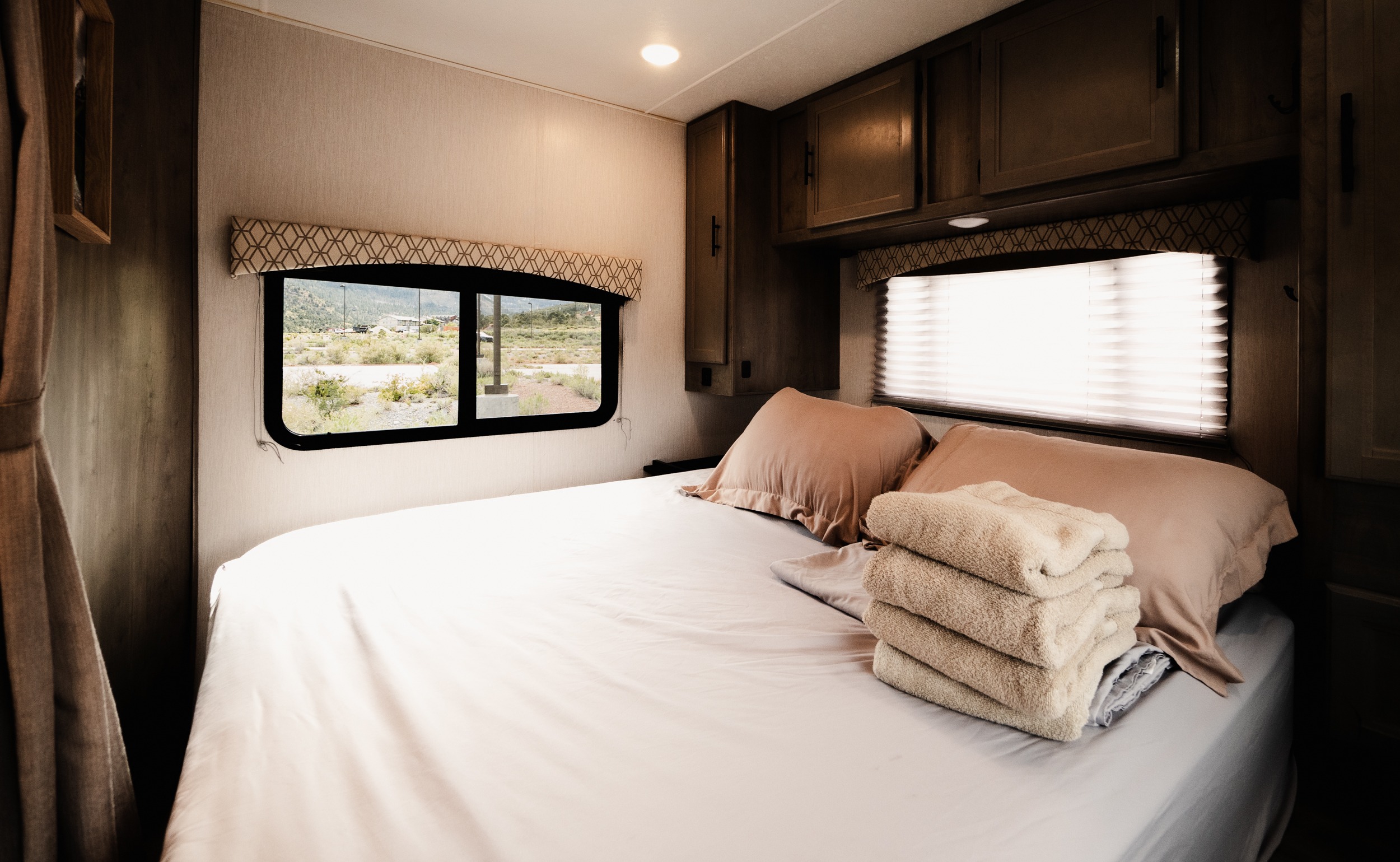 Comfortable RV rental bedroom with a cozy bed, fresh towels, and a scenic desert view from the window.. Coach House FREELA 2020