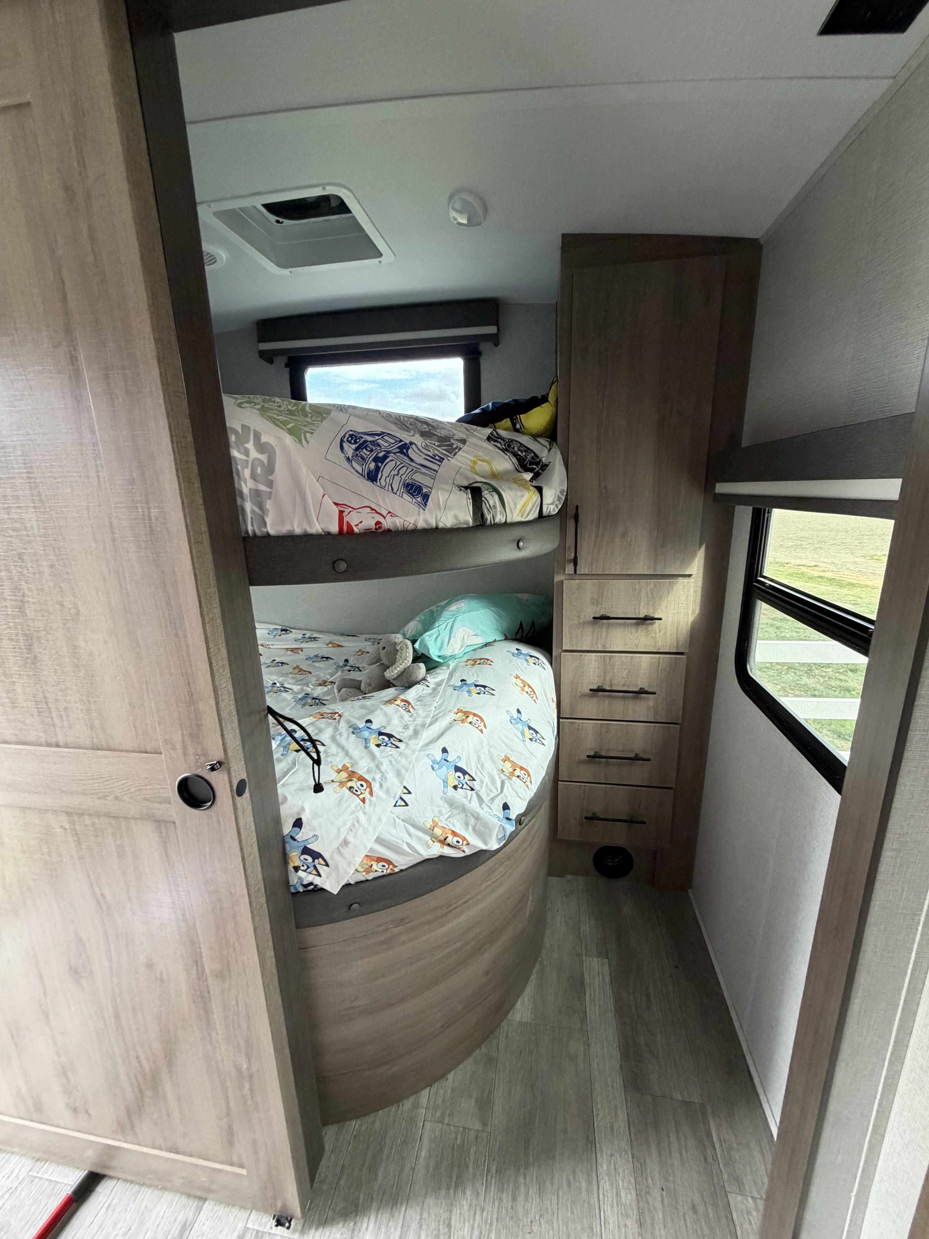 Cozy RV rental sleeping area: bunk beds with fun character bedding, storage, and a bright window for family trips.. Grand Design Imagine 2022