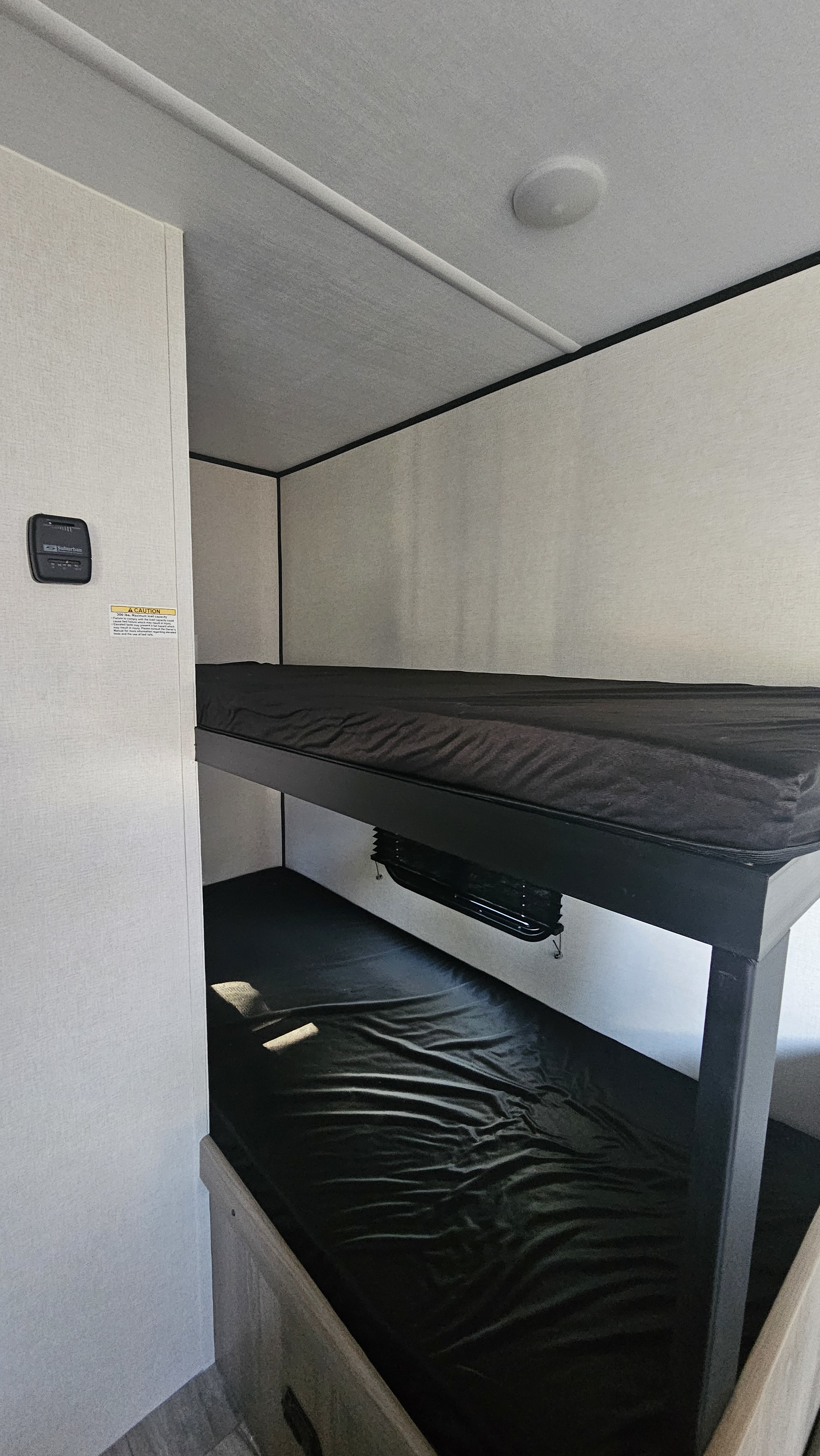 Modern RV rental interior: spacious bunks with dark mattresses, perfect for cozy family travel adventures.. Keystone RV Coleman Light 17Bx 2026