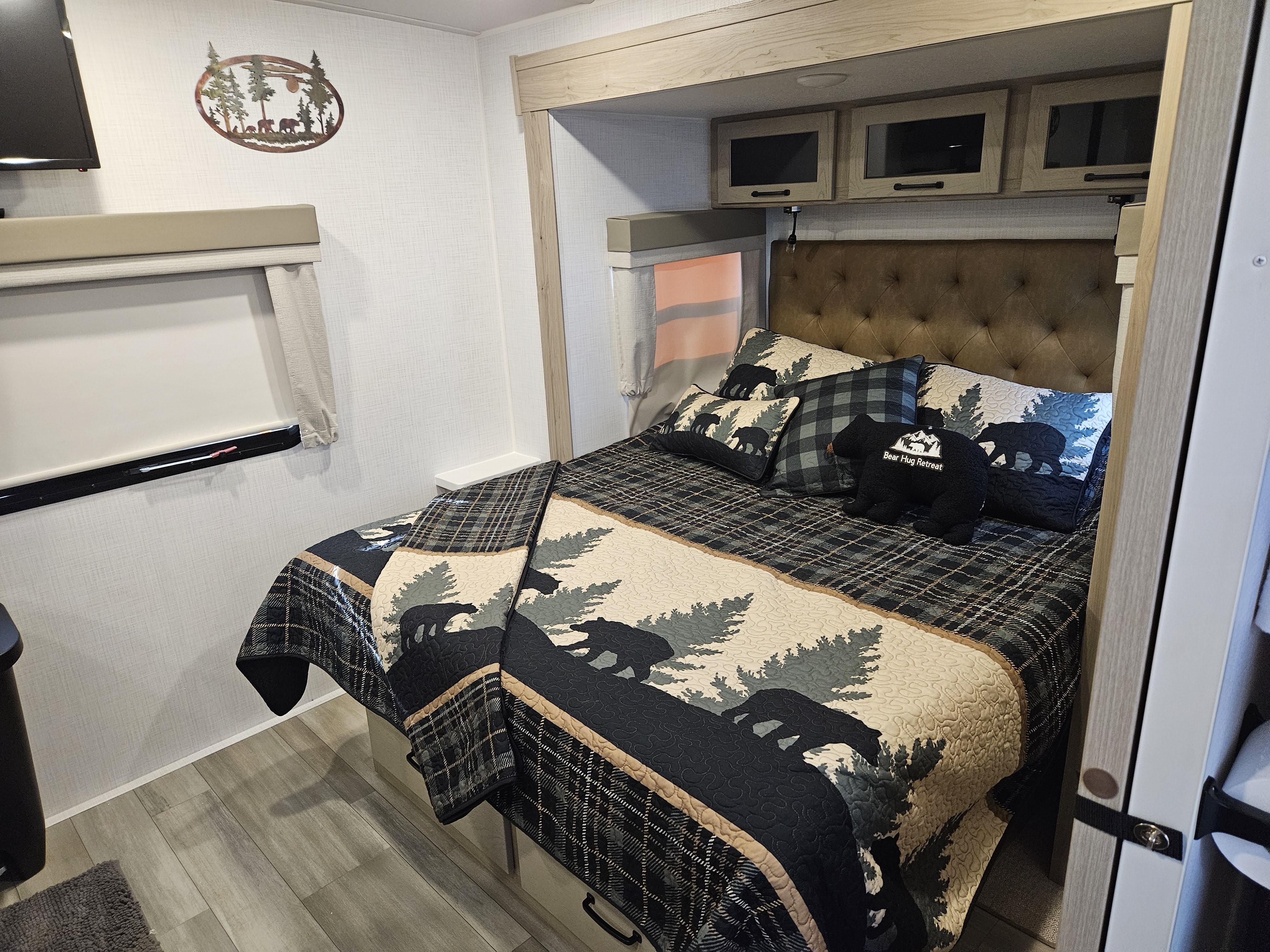 Cozy, bear-themed rv rental bedroom features a plaid quilt, tufted headboard, and woodland decor for a comfy stay.. Forest River Flagstaff Micro Lite 2024