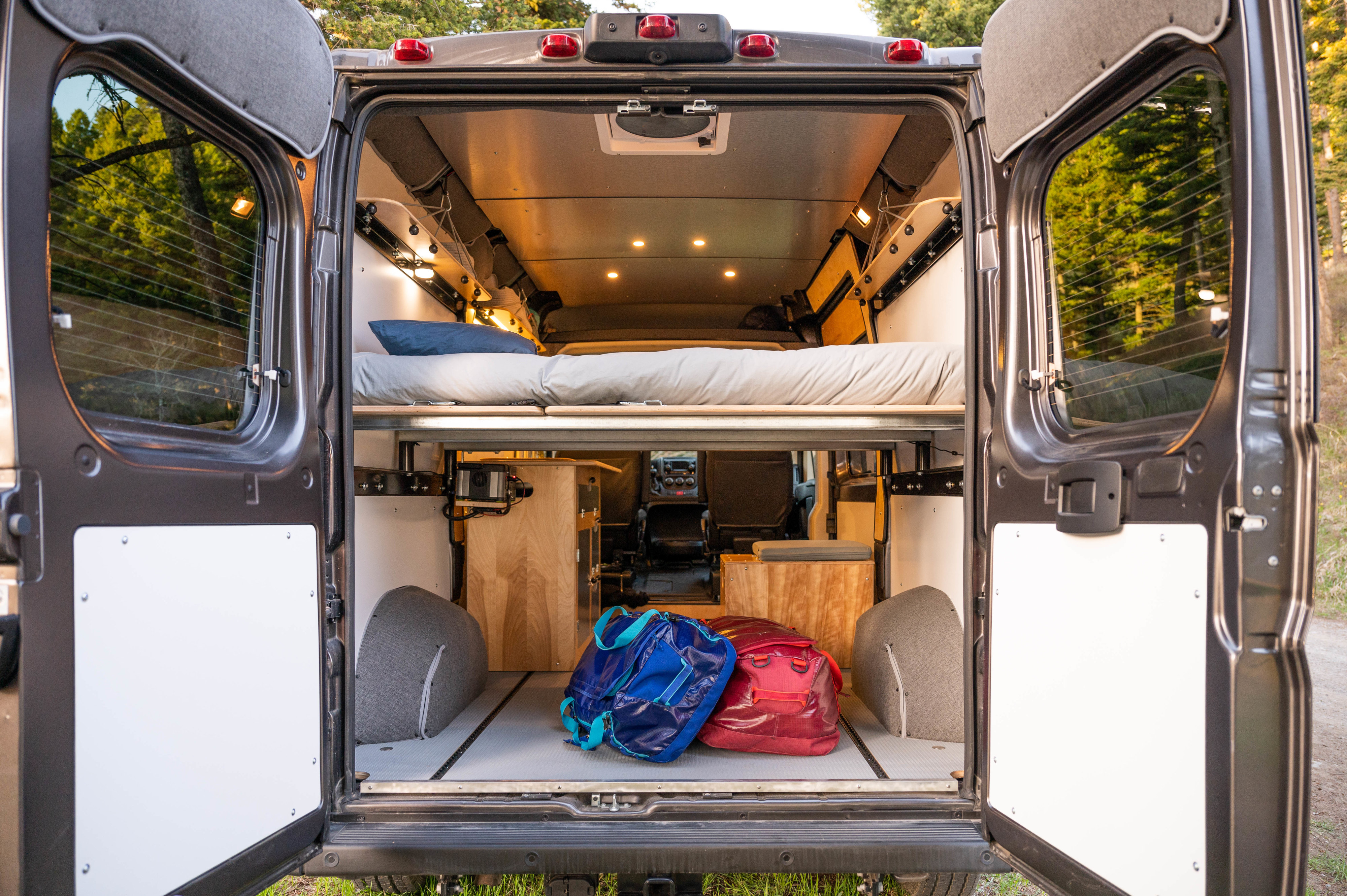 Spacious camper van interior, perfect for your next RV rental adventure. Features a comfy bed, ample storage, and warm lighting.. RAM Promaster 1500 2021