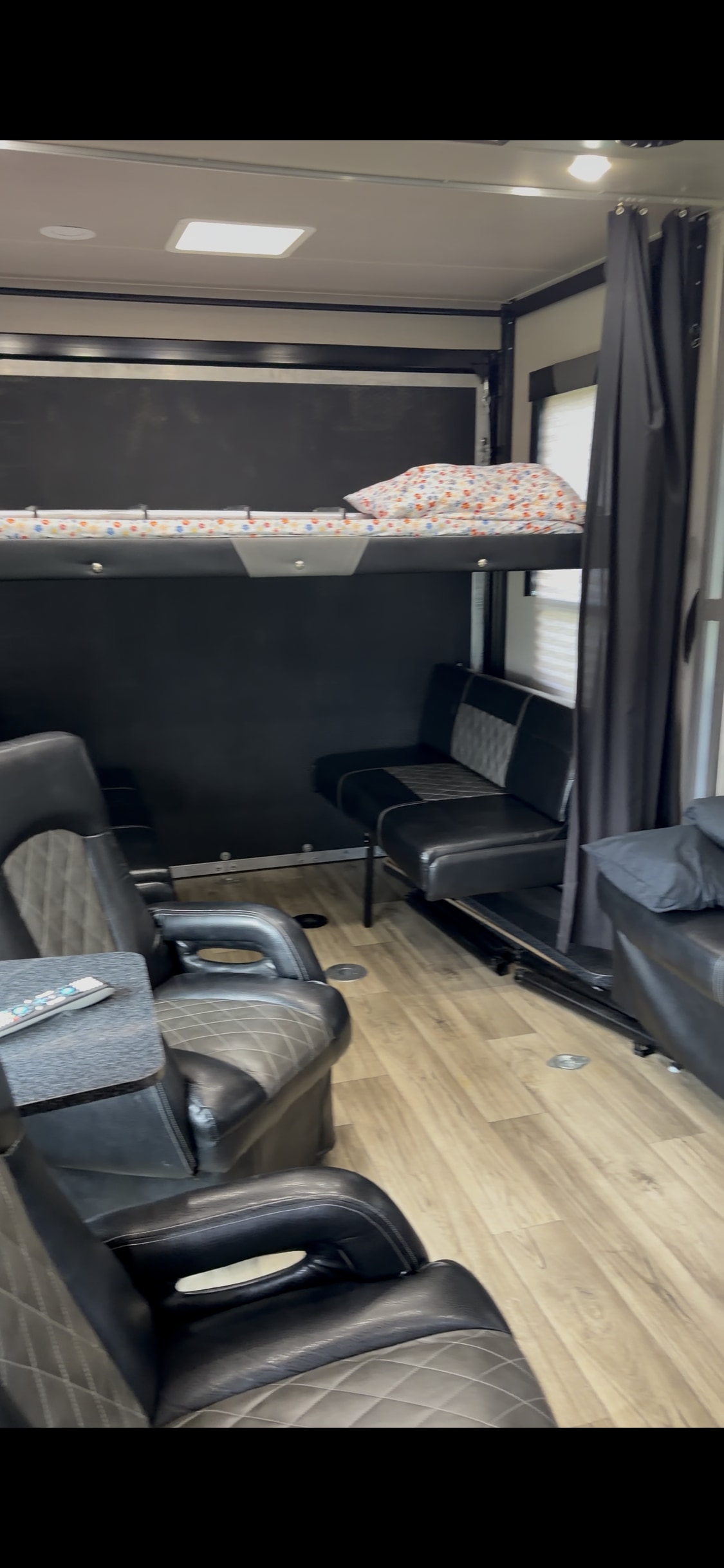 RV rental interior: Features a bunk bed, black and grey recliners, additional seating, and light wood-look flooring.. Genesis Supreme Rv Genesis Supreme 2019