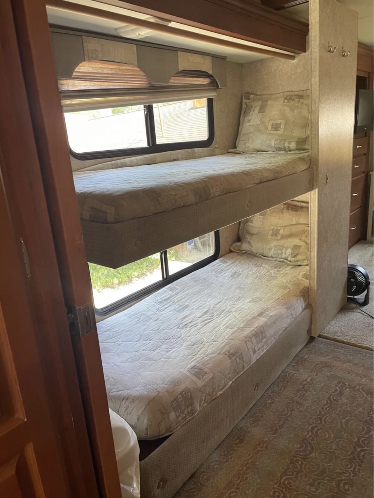 RV rental interior featuring two stacked bunk beds, each with a mattress, bedding, and an adjacent window with outdoor views.. Four Winds Hurricane 2007