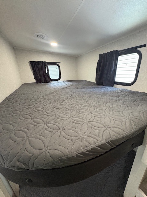 Comfortable bunk beds in this rv rental, featuring grey quilted bedding & windows. Perfect for family travel.. Jayco Eagle 2026