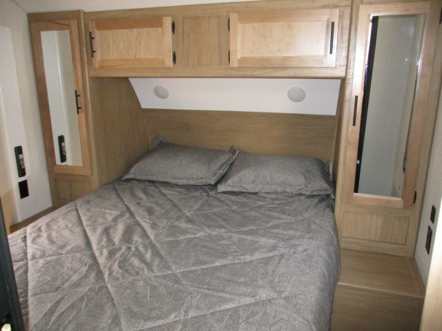 Cozy RV rental bedroom featuring a grey bed, light wood cabinets, and mirrored wardrobes for a comfortable camper interior.. Forest River Cherokee Grey Wolf 2023