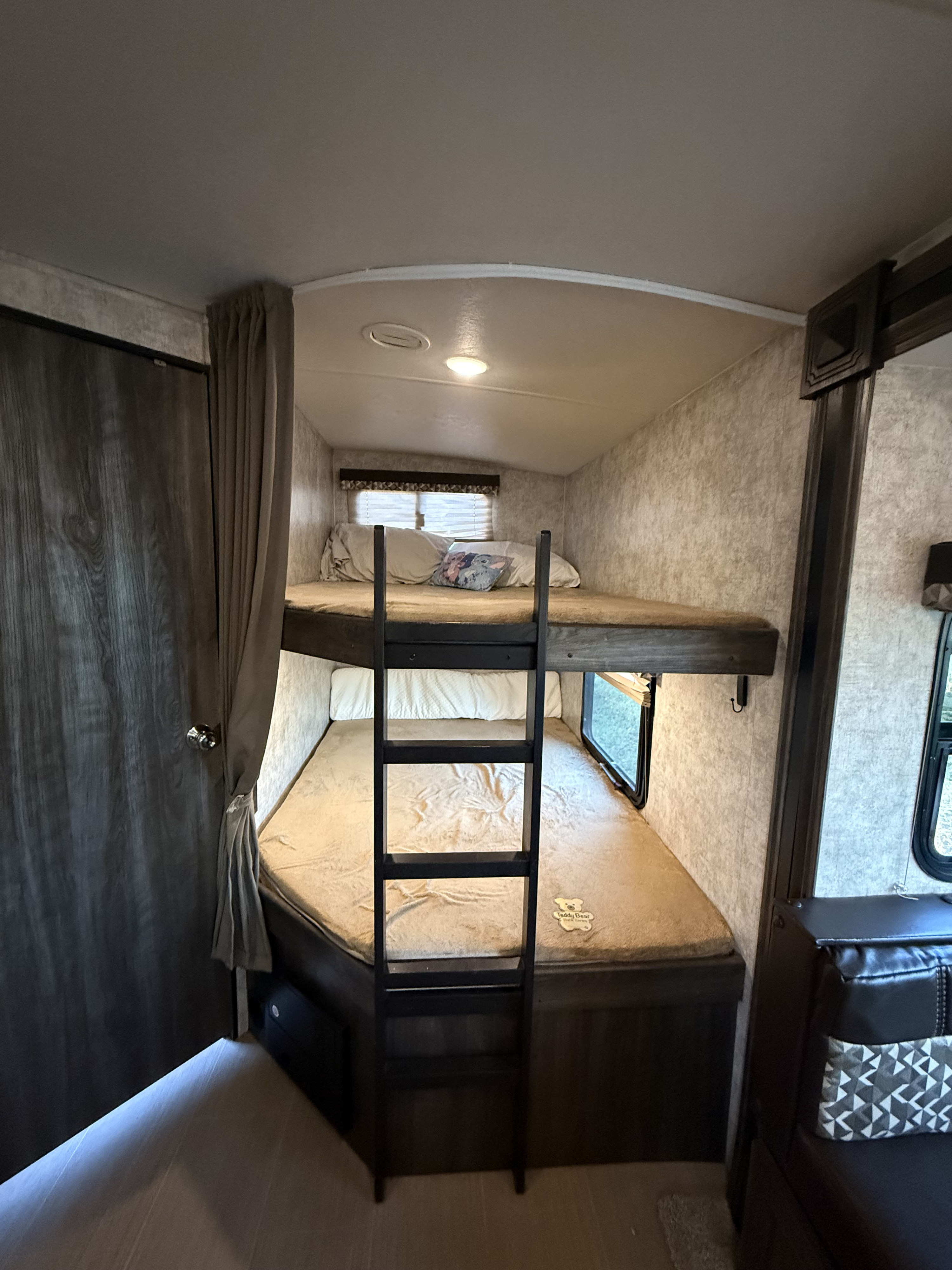 Inside this rv rental: a cozy bunk bed area with two beds, a ladder, windows, and warm lighting. Ideal for family travel.. Highland Ridge RV Open Range Ultra Lite 2018