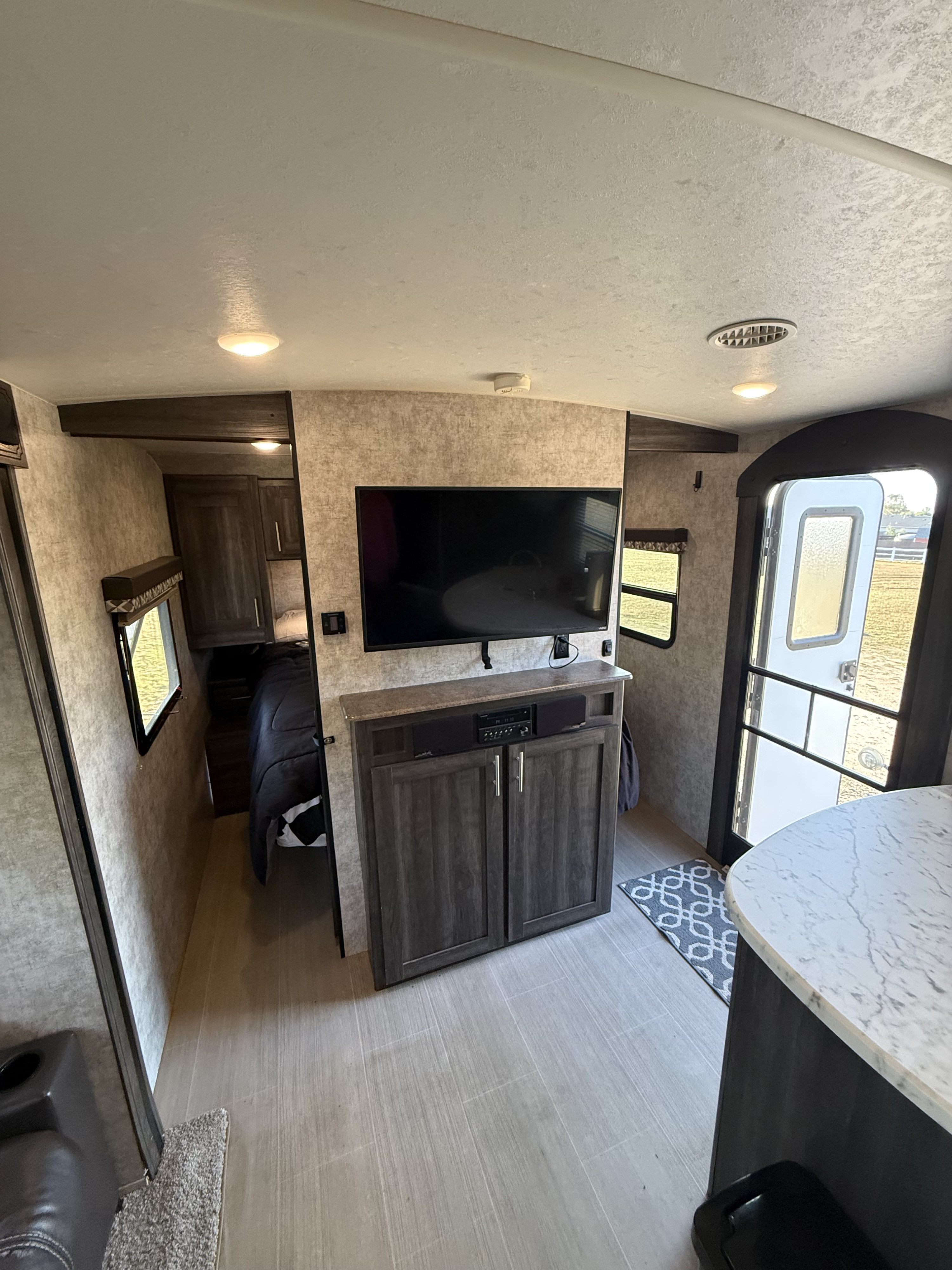 Modern RV rental interior: TV, entertainment console, cozy bedroom, and bright entry. Ready for your travels.. Highland Ridge RV Open Range Ultra Lite 2018