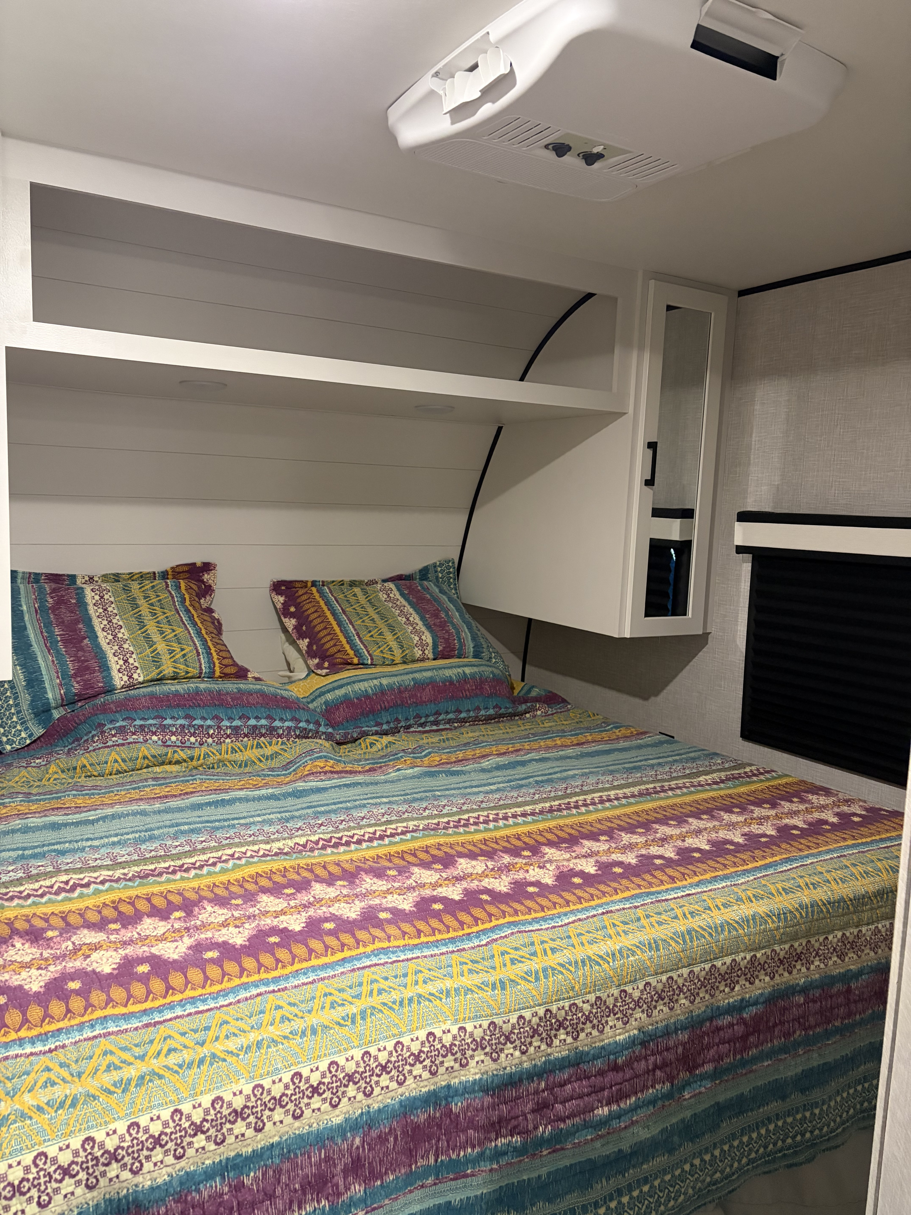 Cozy RV rental bedroom with colorful patterned bedding, overhead storage, and AC unit for a comfortable stay.. Jayco Jay Flight SLX 2025