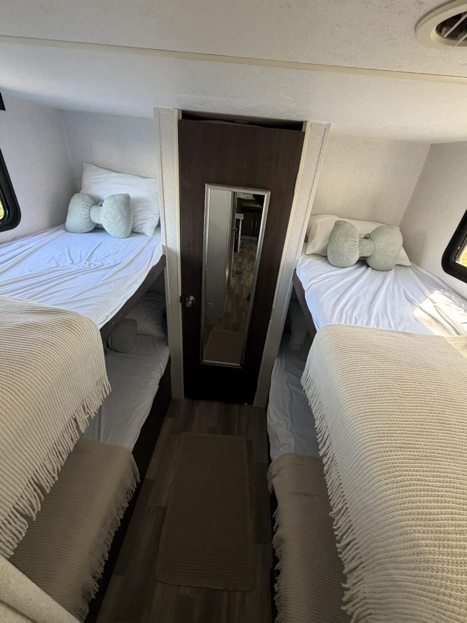 Cozy RV rental sleeping area featuring two sets of bunk beds with white bedding, comfy blankets, and unique bow-shaped pillows.. Forest River Wildwood 2020