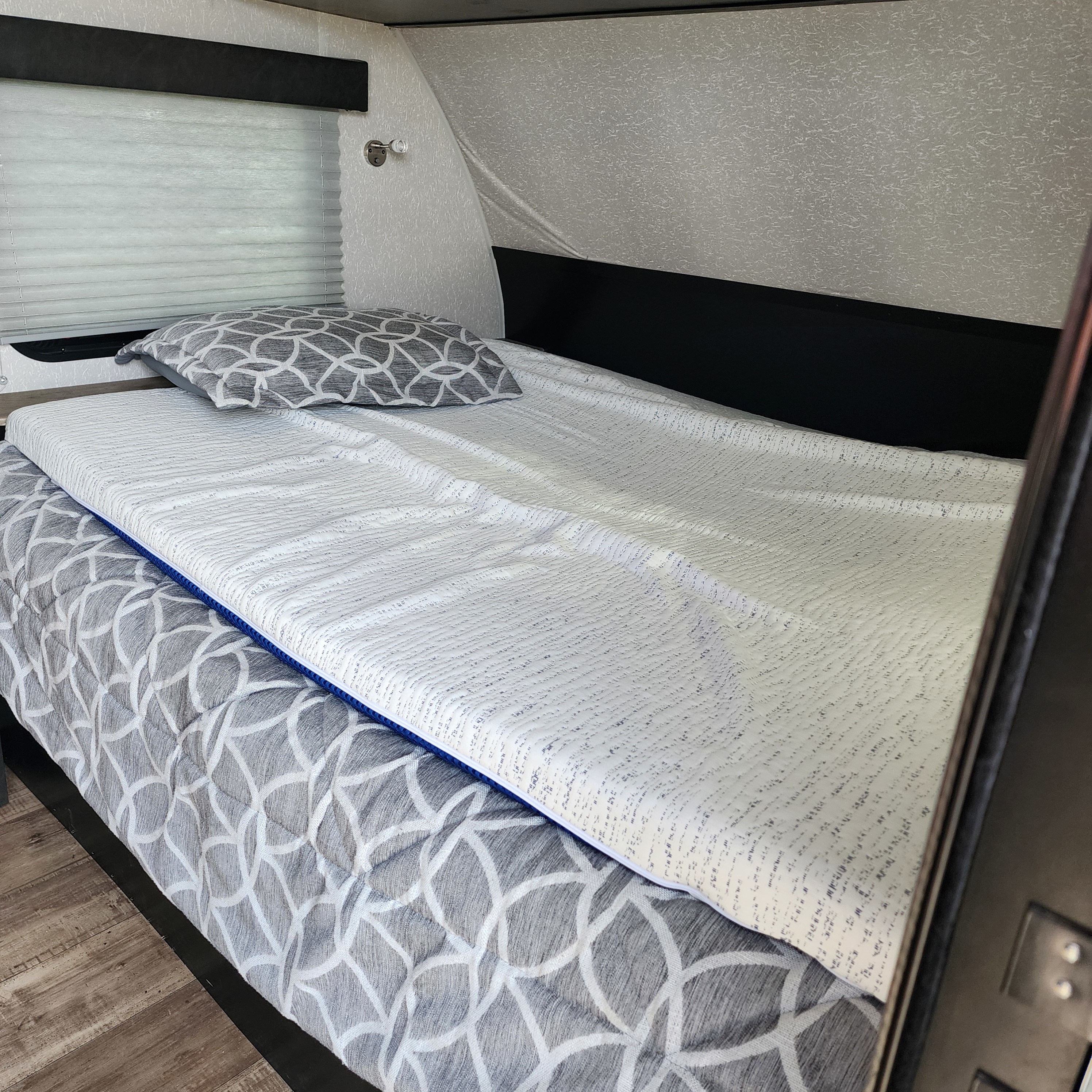 Cozy rv rental interior with a bed made up with gray patterned bedding, a white textured mattress topper, and window blinds.. Forest River Cherokee Wolf Pup Black Label 2022