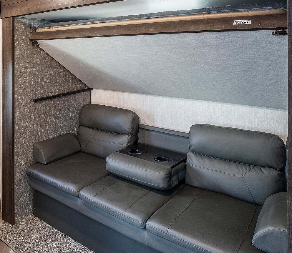 RV rental: Modern interior featuring a cozy sofa with recliners & cup holders, and a compact fold-down bunk bed.. Sportsmen LE 2020