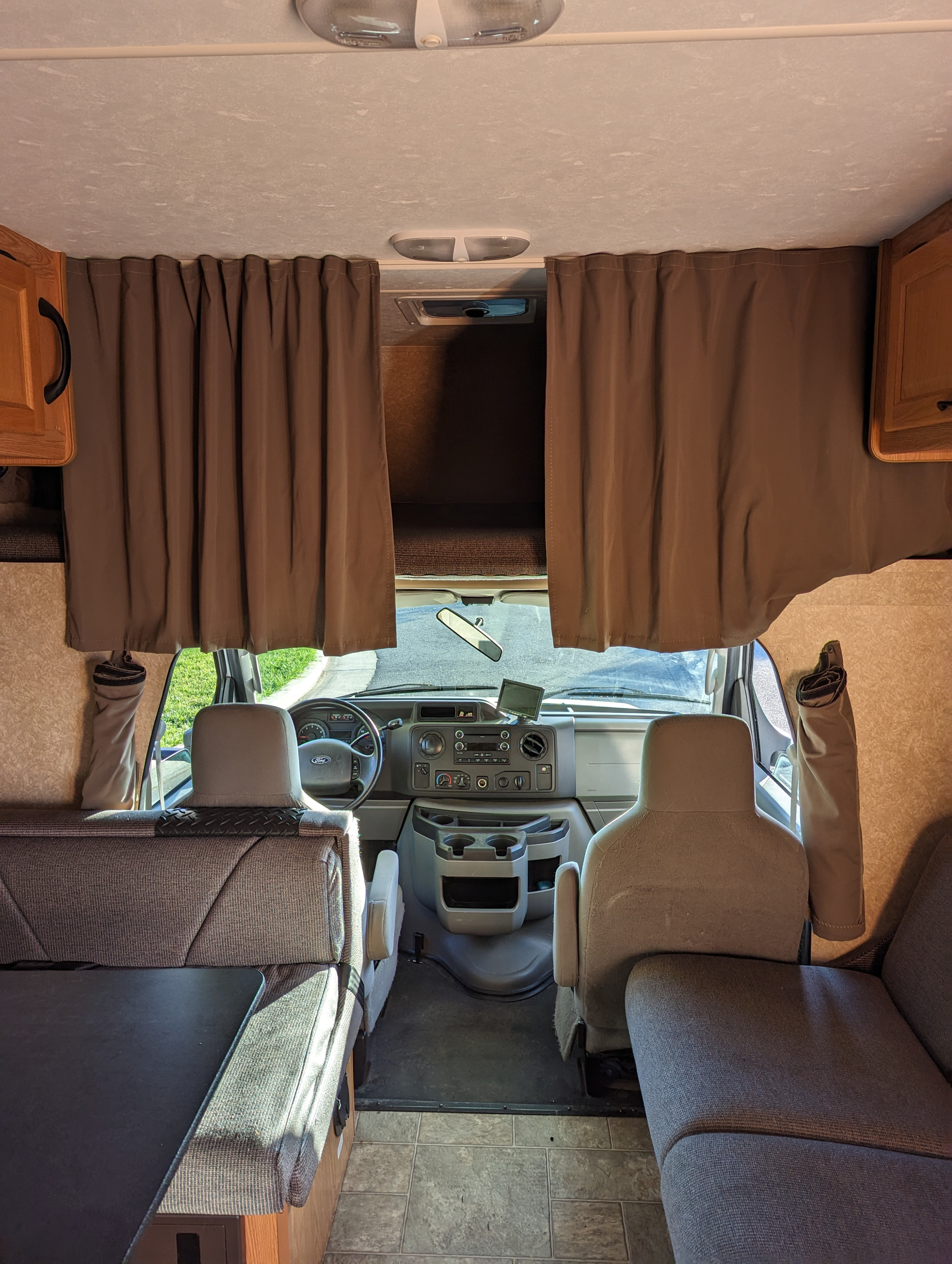 Inside an RV rental, looking forward past the dining booth & couch to the driver's cab with an overhead bed.. Thor Majestic 2016