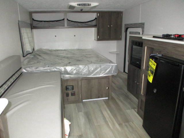 Cozy RV rental interior showing a comfortable bed, dinette, and compact kitchen with fridge & microwave.. Viking Viking Express 2022