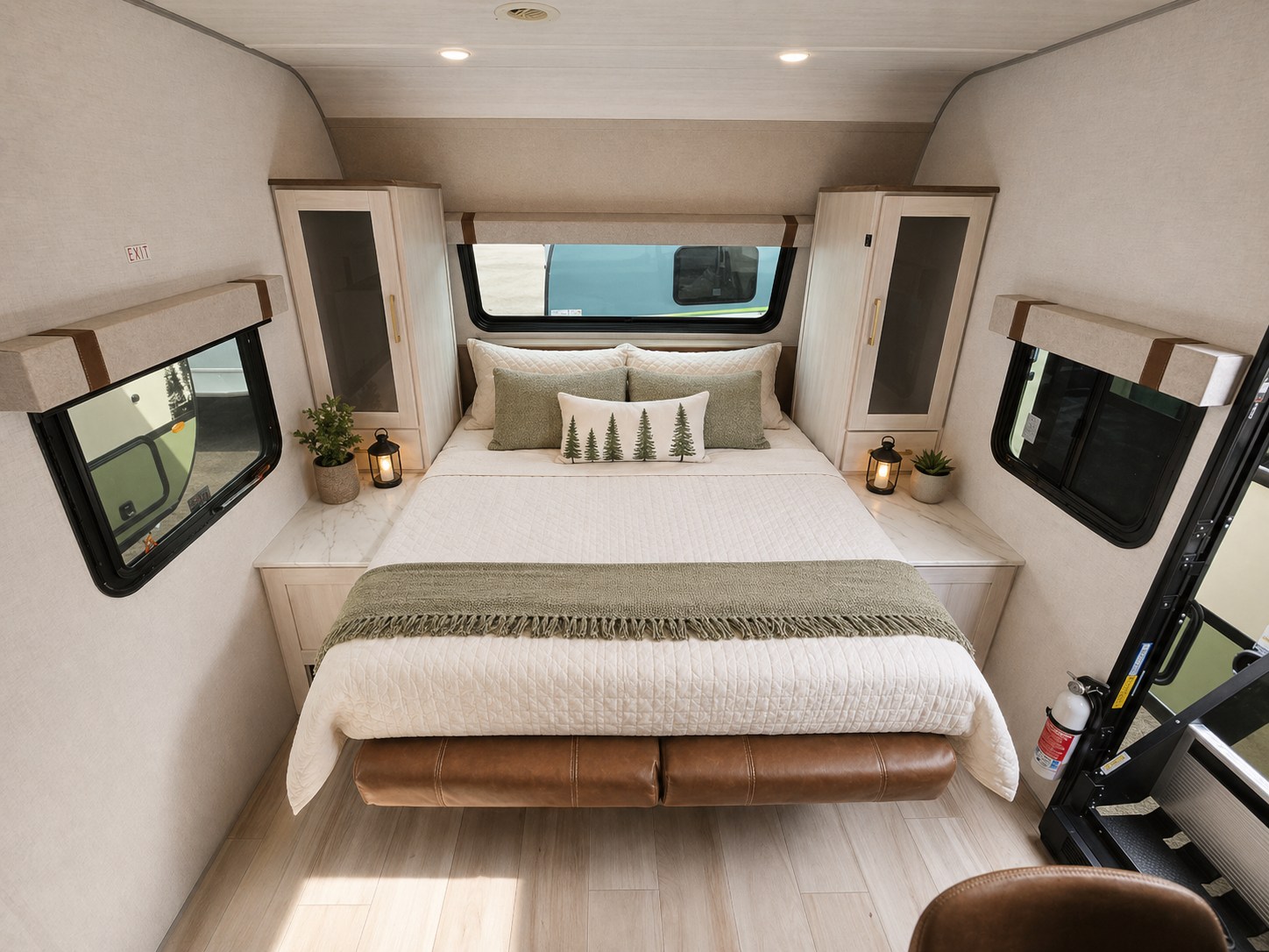 Inside a bright rv rental bedroom, a large bed with white and green bedding, flanked by windows and light wood cabinets, offers comfort.. Forest River No Boundaries NB20.3 2026